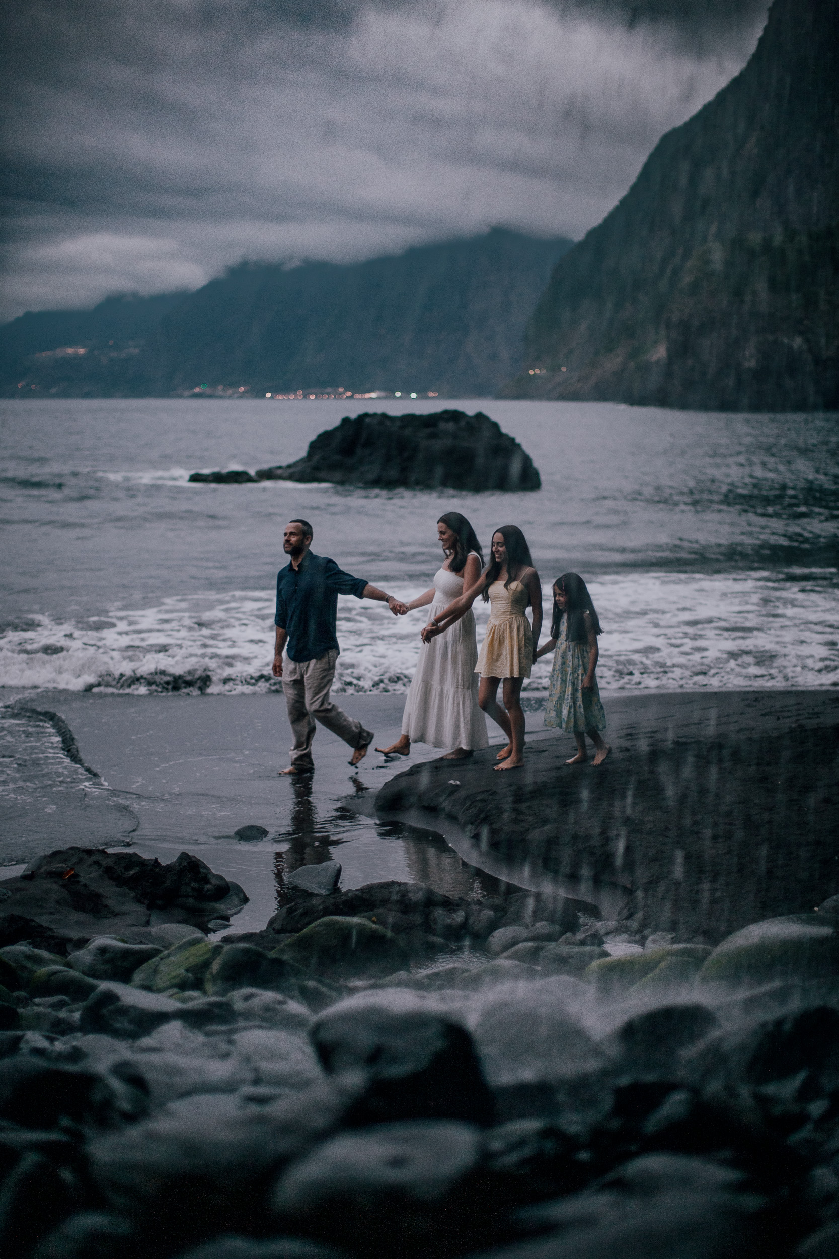 The family joining hands in the shallows at dusk, Seixal, Madeira
