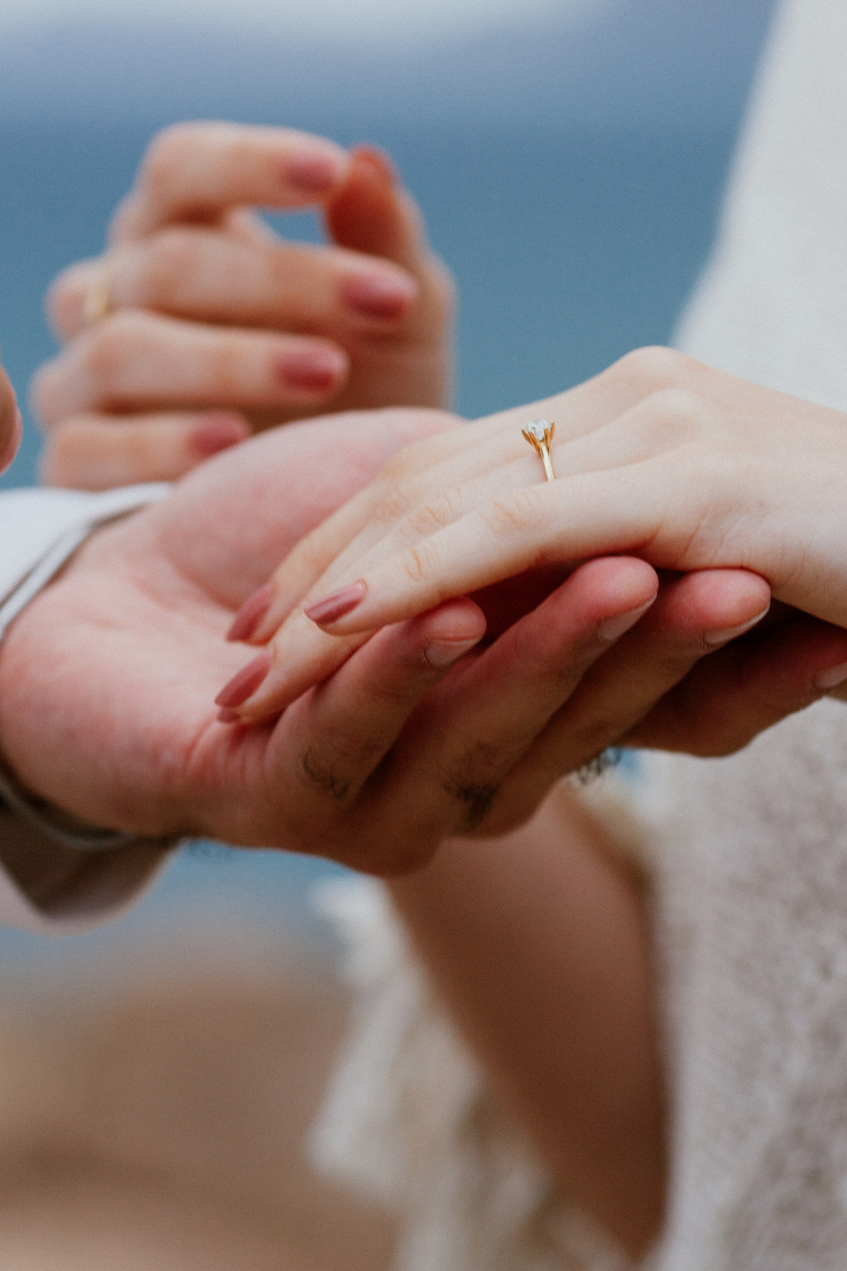 Close-up of Isabela's hand with the new gold ring resting in Lucas's palm, Miradouro do Guindaste, Madeira