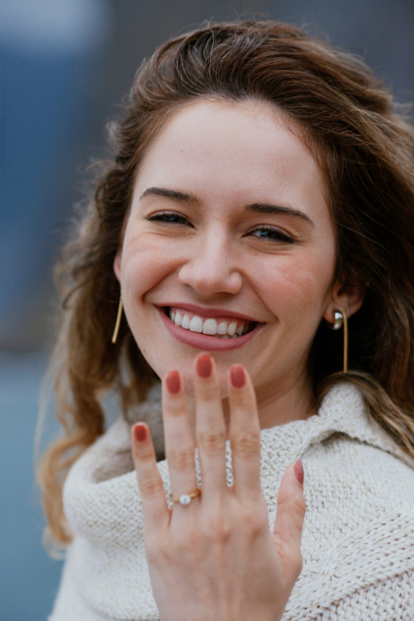 Isabela smiling at the camera and holding up her ring hand, cream knit wrap, Miradouro do Guindaste, Madeira