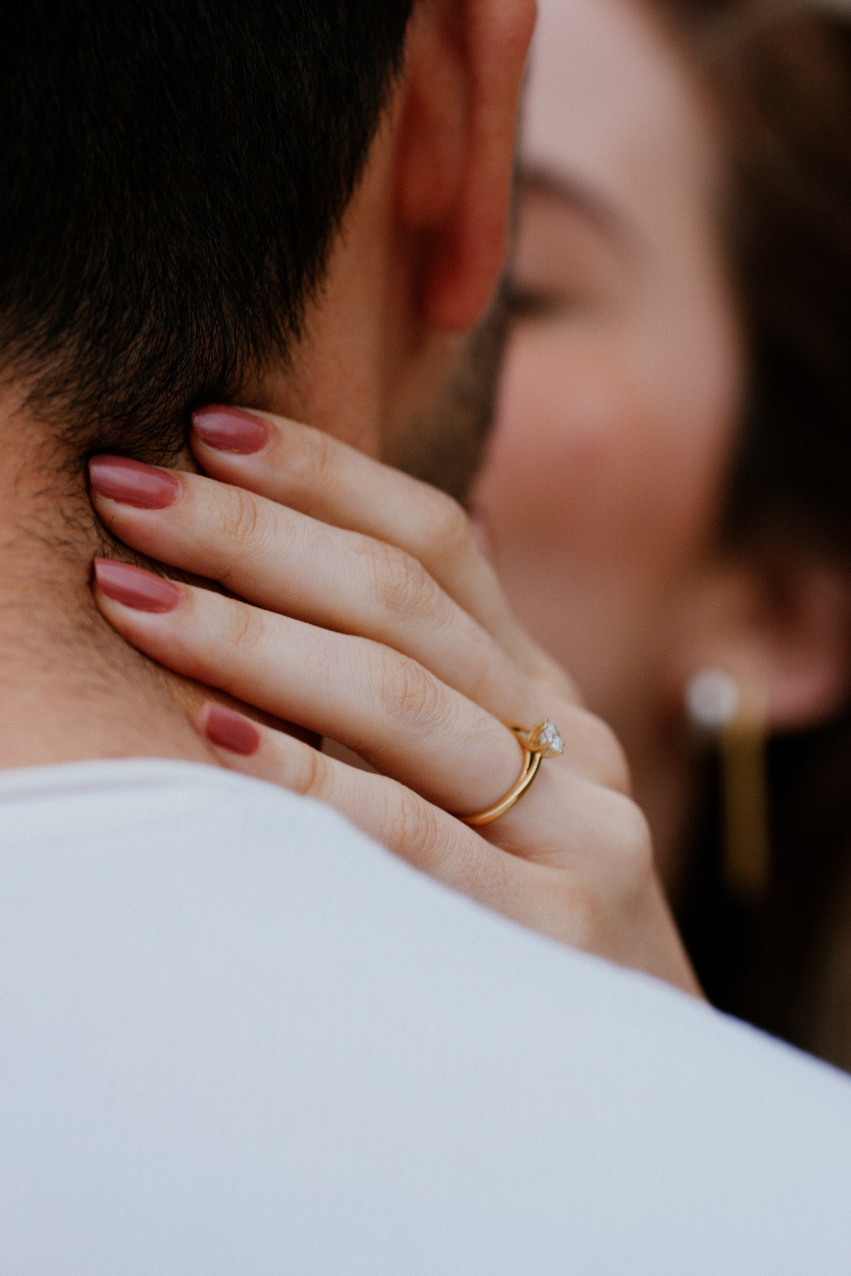 Vertical close-up of Isabela's ring hand on Lucas's neck during a kiss, Miradouro do Guindaste, Madeira