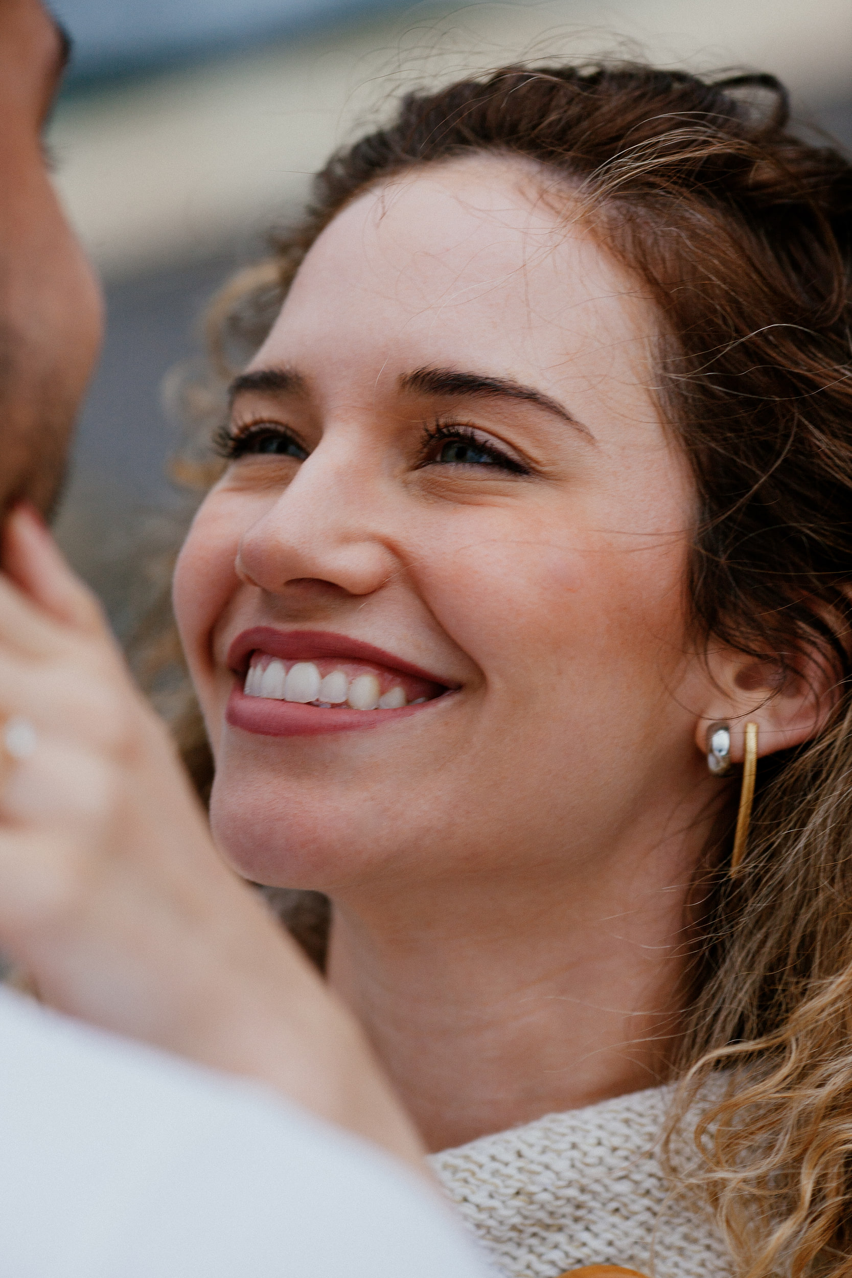 Isabela laughing up at Lucas, her curls loose in the wind, Miradouro do Guindaste, Madeira