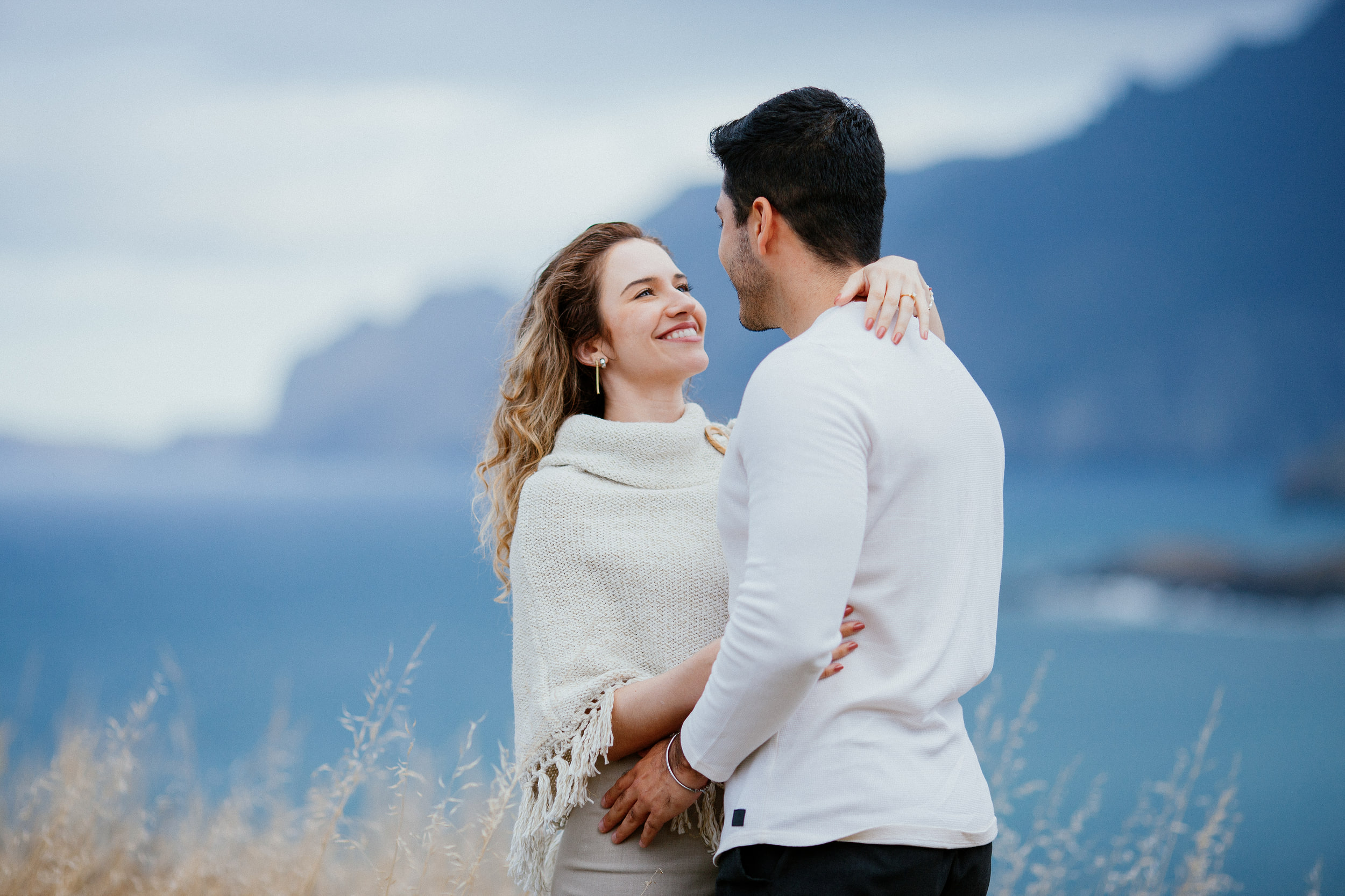 Lucas and Isabela embracing above the ocean, high cliffs of the north coast behind, Miradouro do Guindaste, Madeira