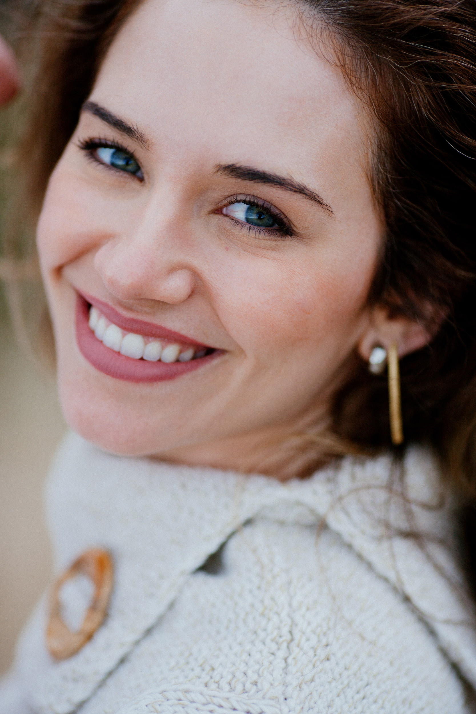 Close portrait of Isabela smiling at the camera, wooden toggle on her knit collar, Miradouro do Guindaste, Madeira