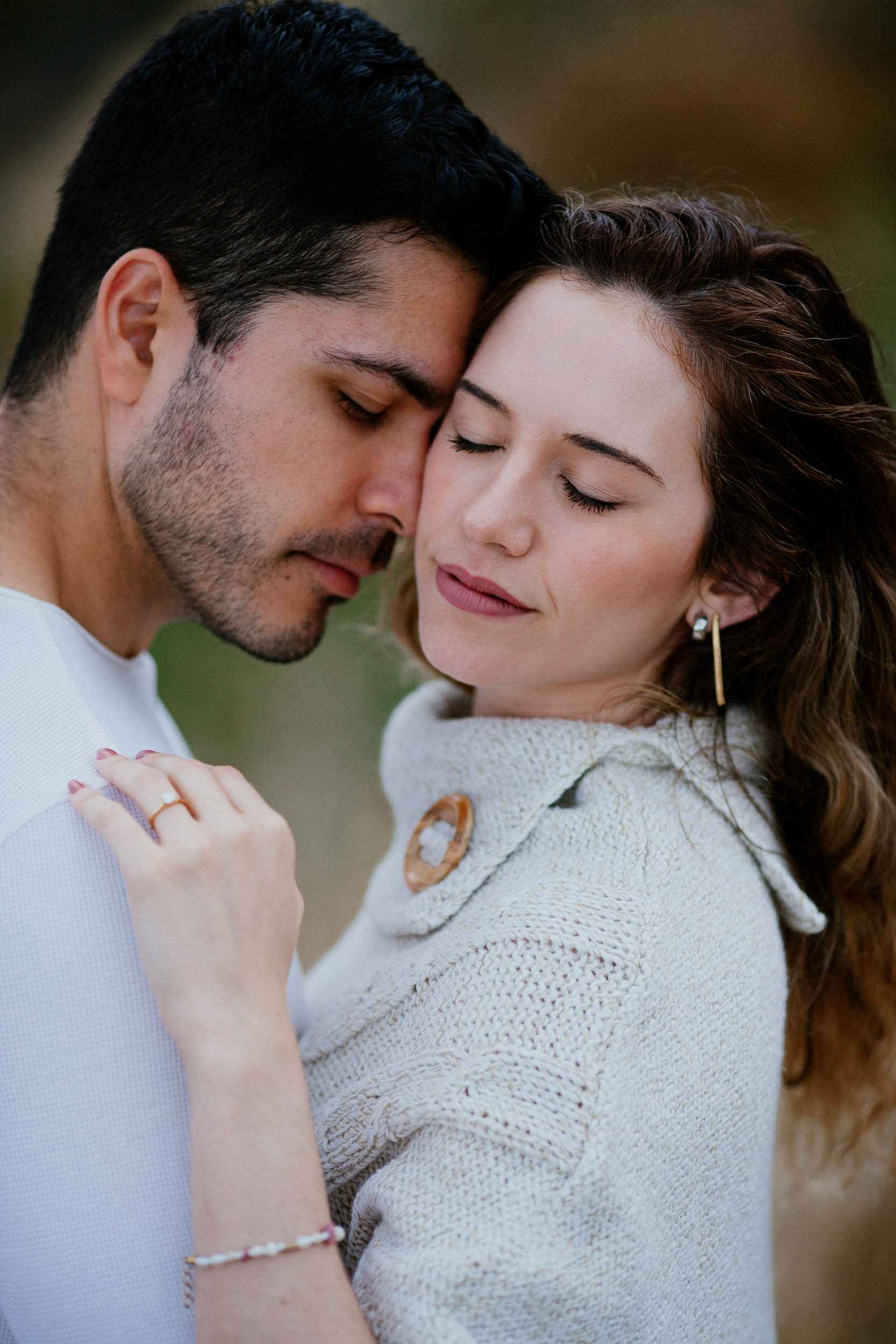 Lucas and Isabela cheek to cheek with eyes closed, her ring hand on his chest, Miradouro do Guindaste, Madeira