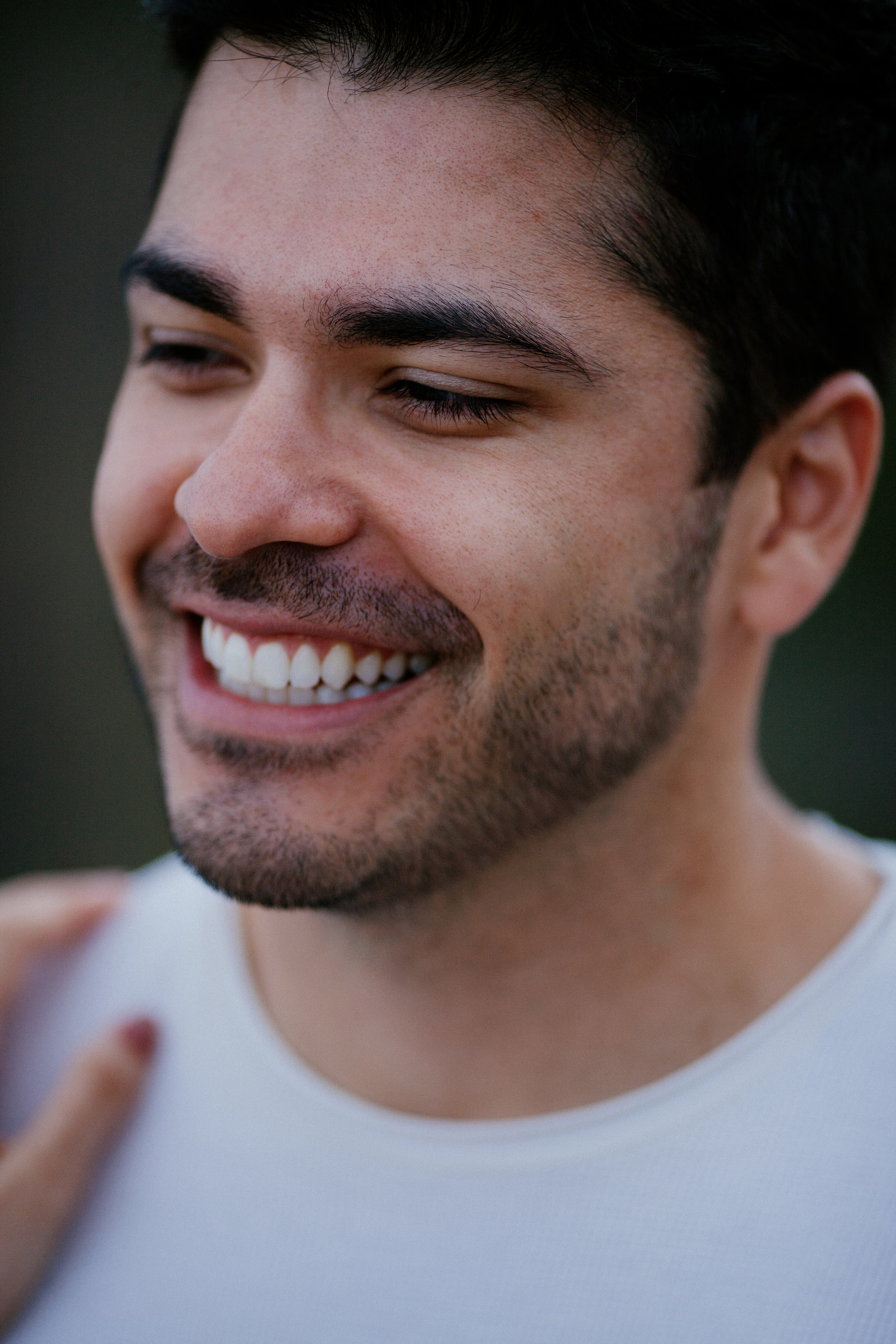 Vertical close portrait of Lucas laughing, Isabela's hand on his shoulder, Miradouro do Guindaste, Madeira
