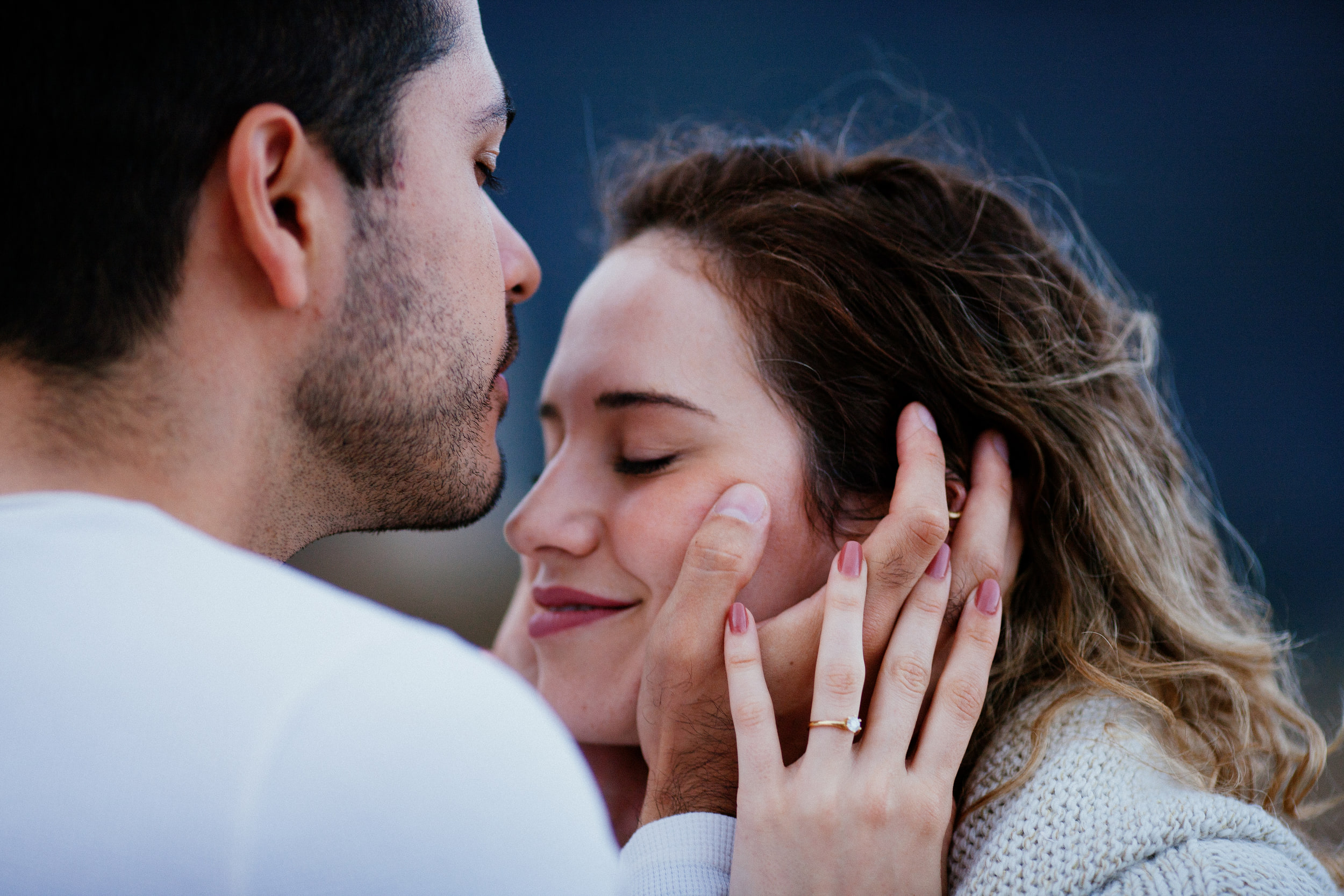 Lucas leaning in for a kiss, Isabela smiling with her eyes closed and her ring hand raised, Miradouro do Guindaste, Madeira
