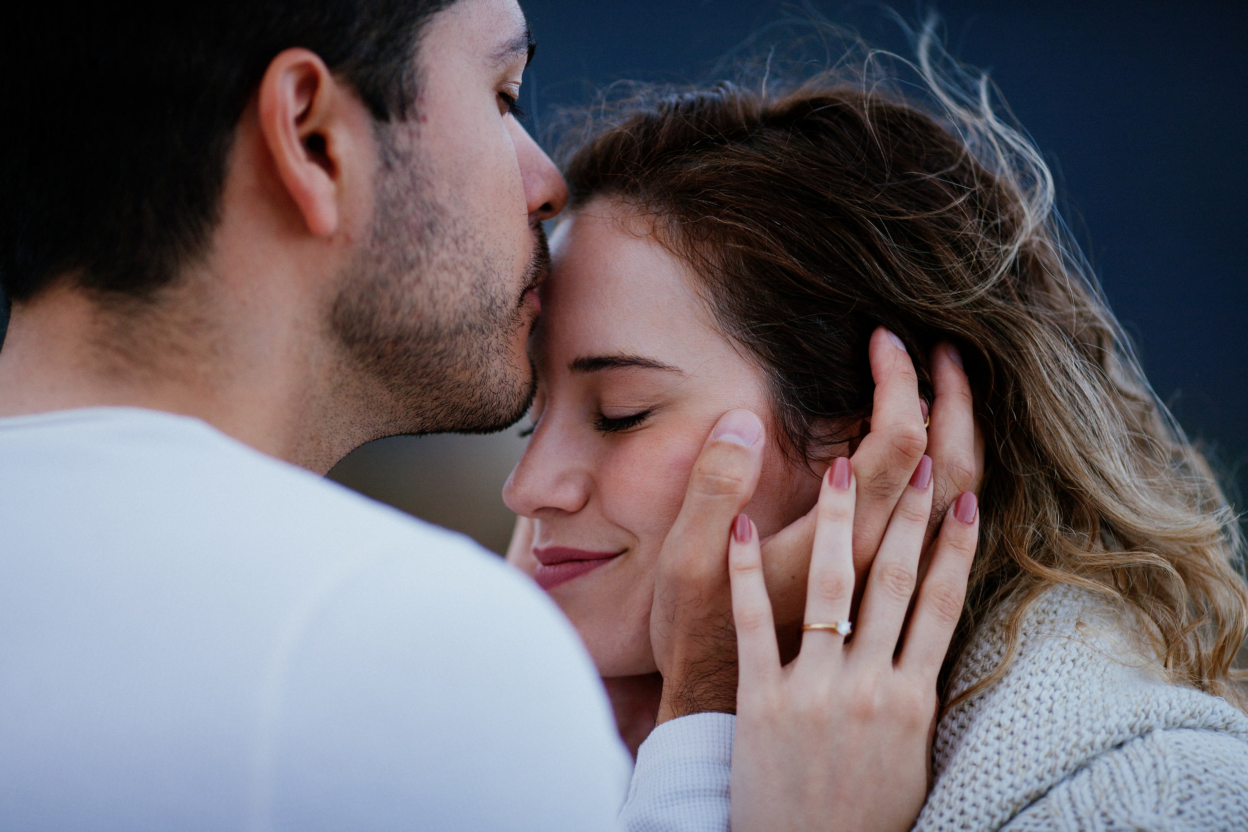 Lucas kissing Isabela's forehead, her hand with the ring on her cheek, Miradouro do Guindaste, Madeira