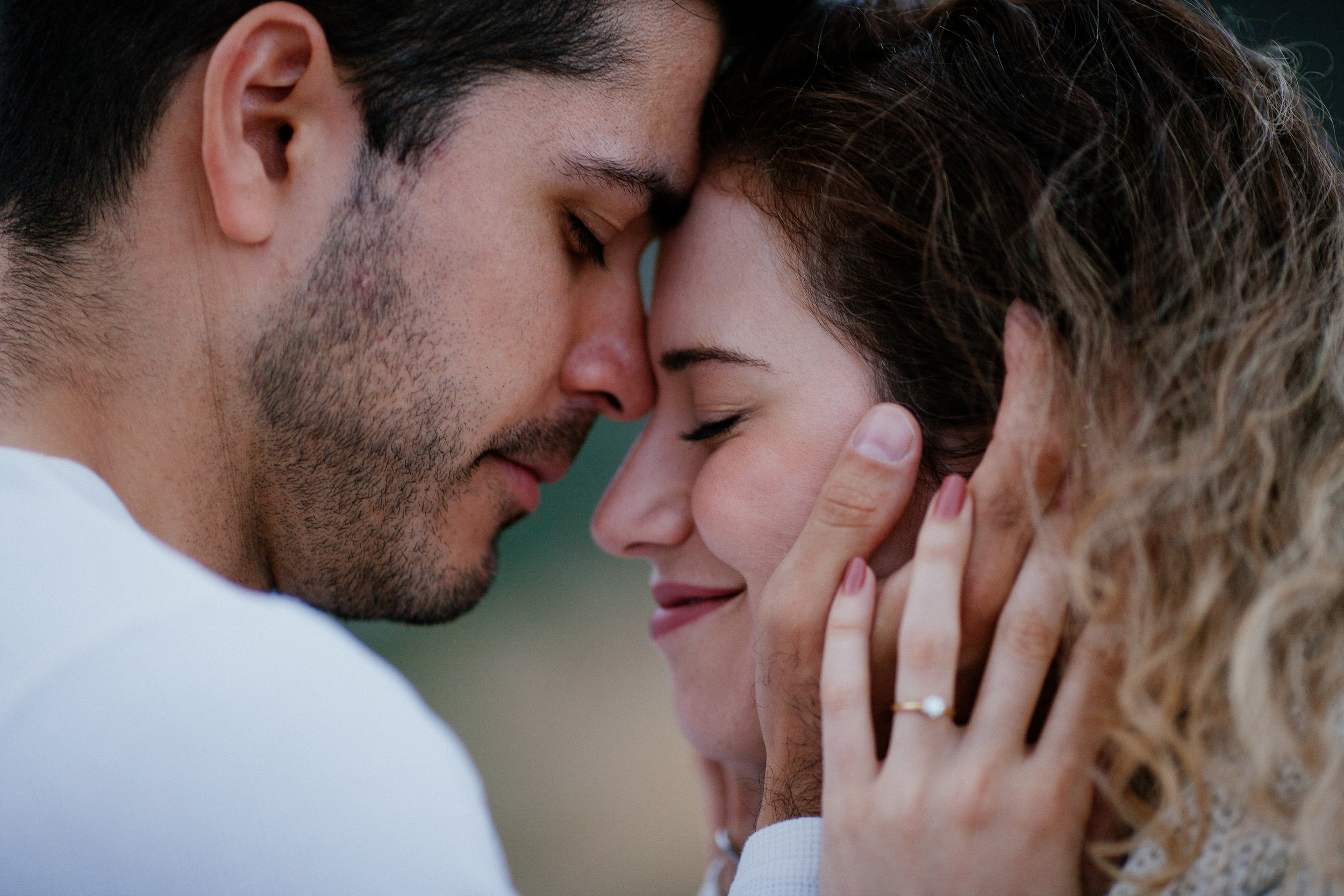 Foreheads touching, eyes closed, Isabela's ring hand against Lucas's cheek, Miradouro do Guindaste, Madeira