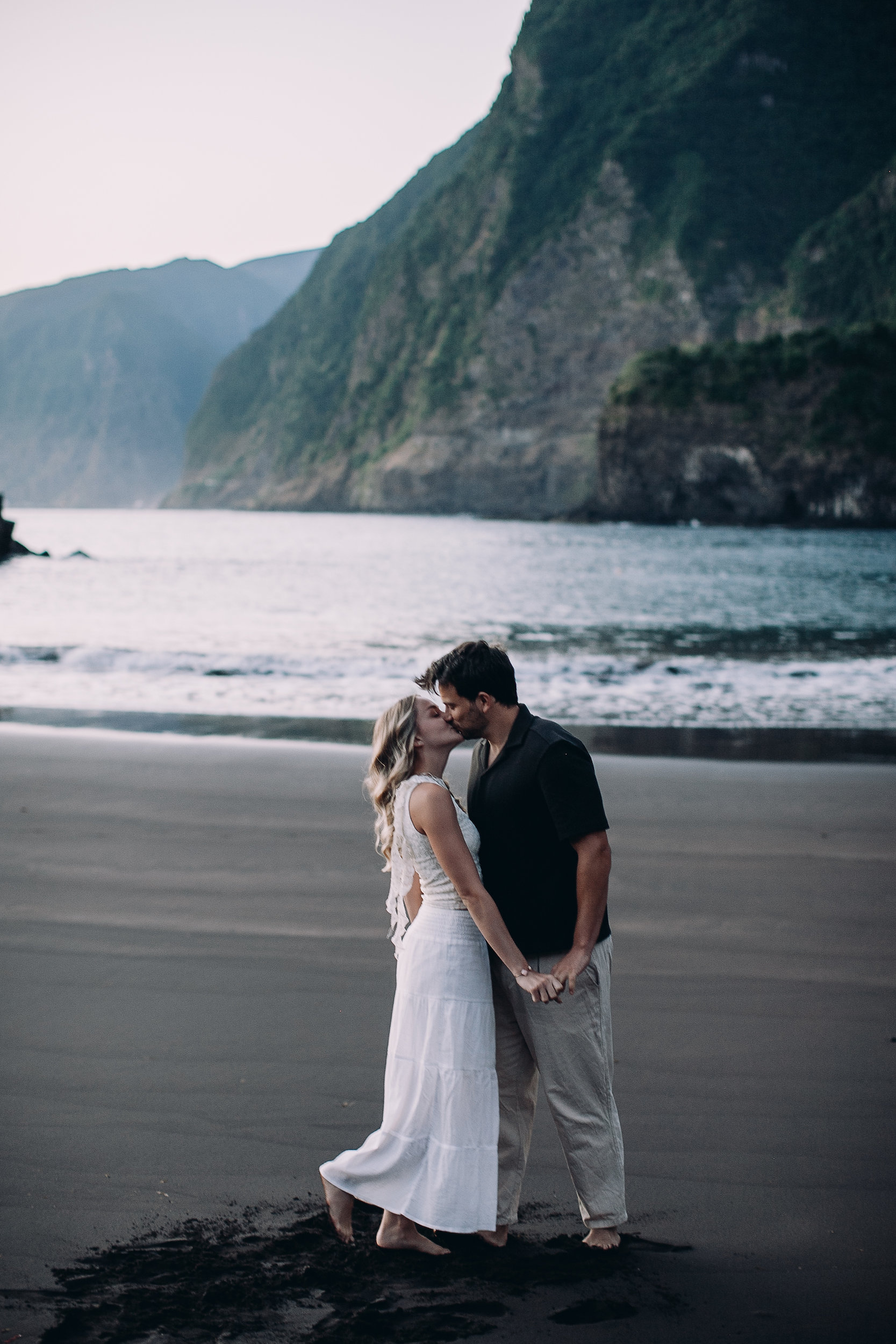 Noah and Laura kissing on the black sand beneath the cliffs, Seixal Beach, Madeira