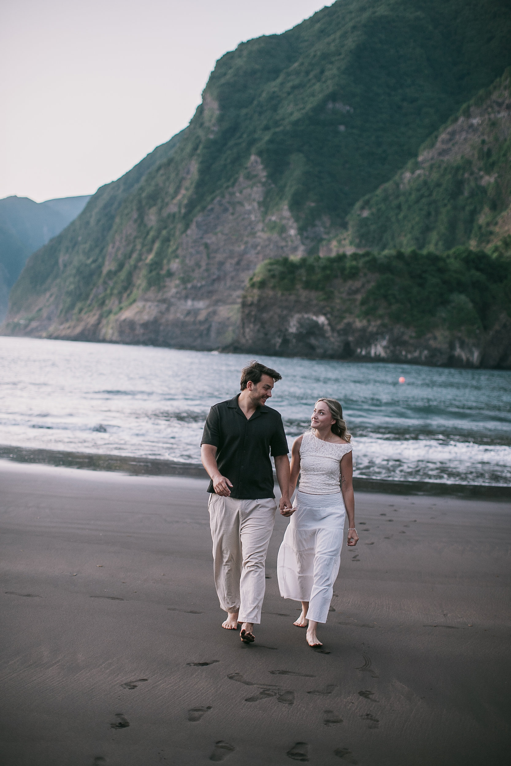 Walking the empty beach together, footprints in the black sand, Seixal, Madeira