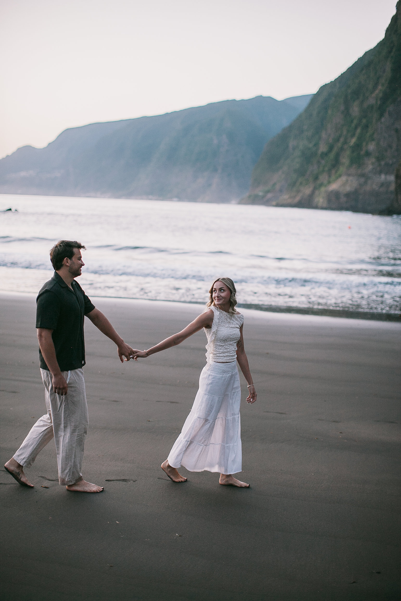 He reaches back for her hand on the wet sand, Seixal, Madeira