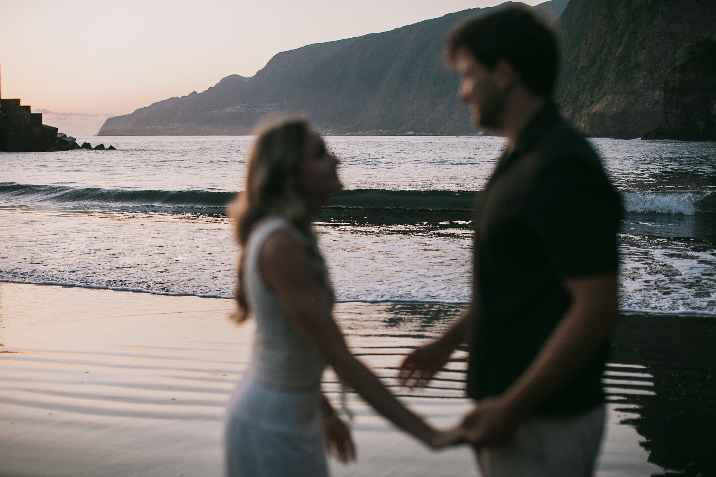 Silhouettes holding hands against the silver water, Seixal Beach, Madeira