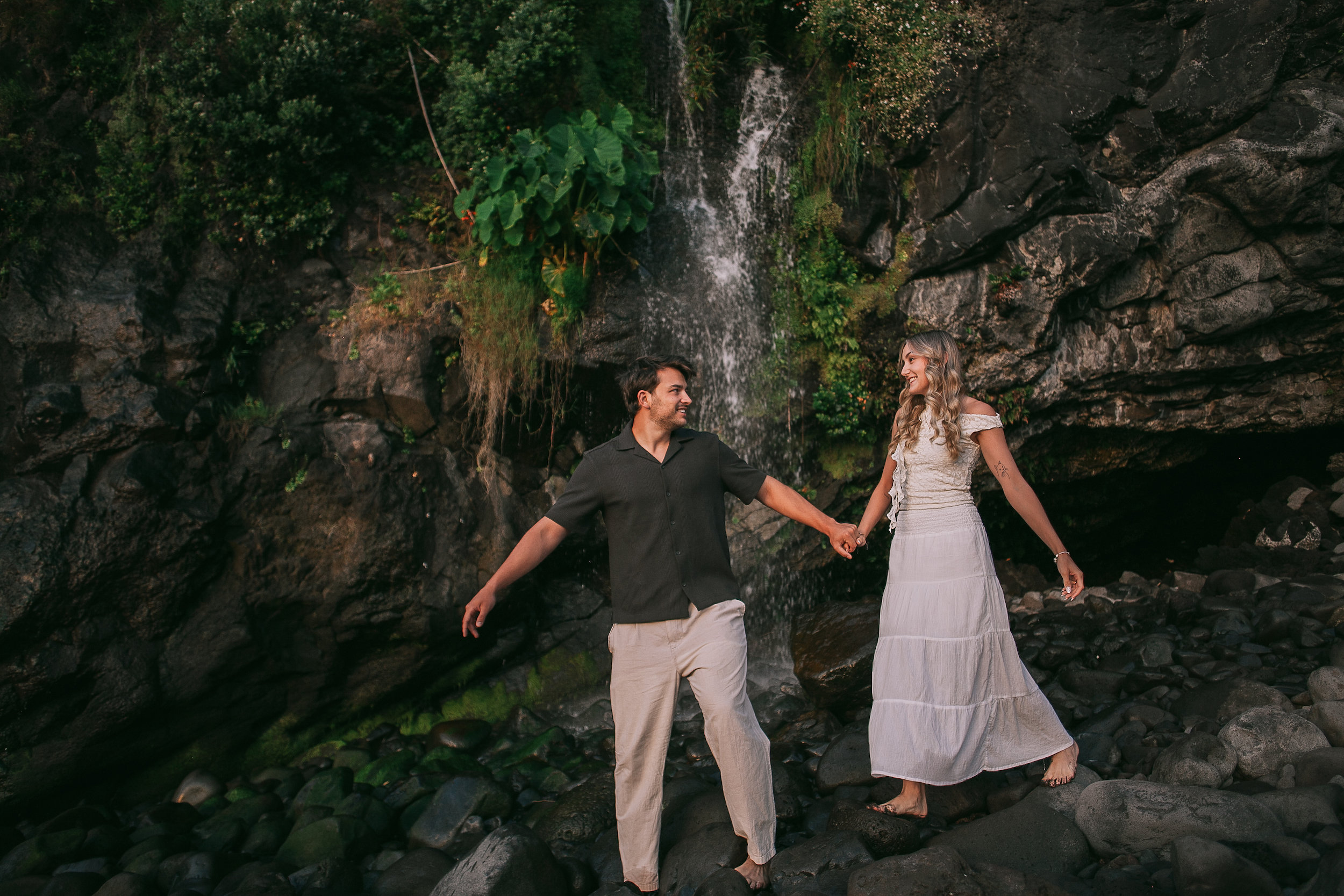 Balancing together on the rocks under the cliffside waterfall, Seixal Beach, Madeira