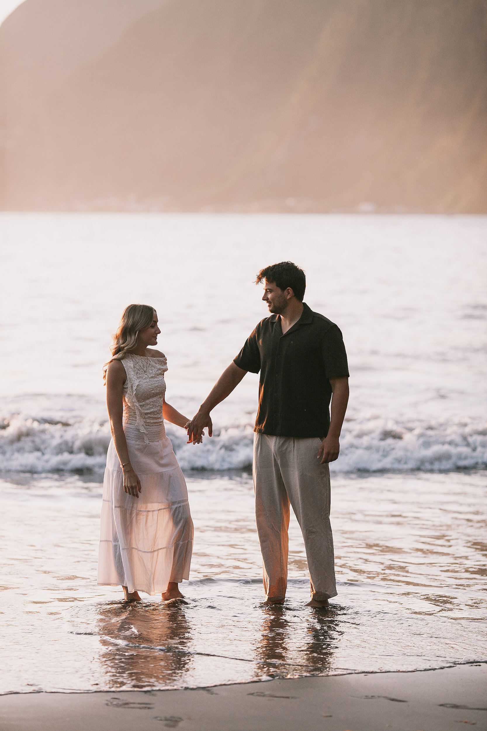 Golden light across the couple in the shallows, Seixal, Madeira