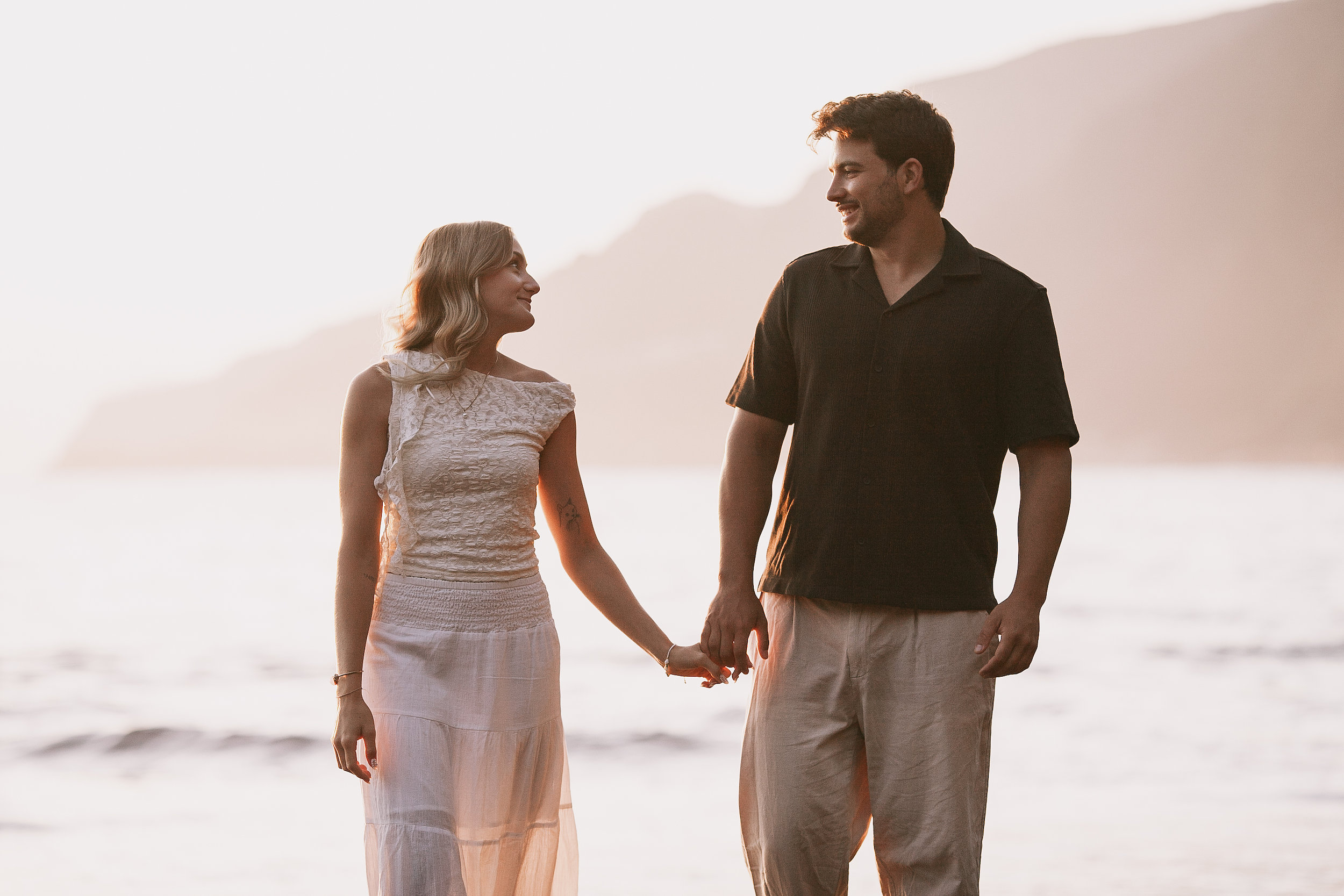 Smiling at each other in the golden mist, cliffs pale behind, Seixal, Madeira