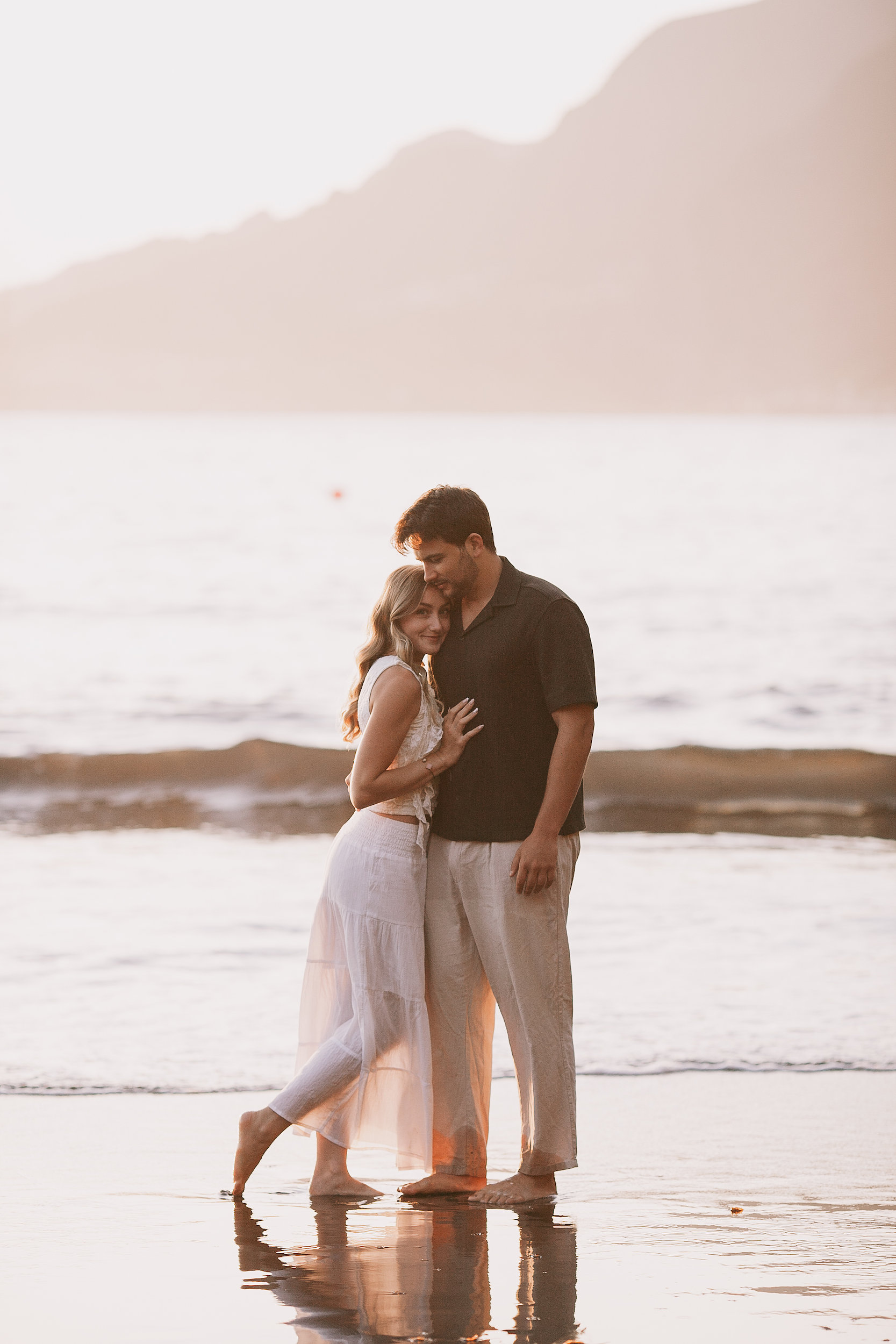 Embracing at the water in warm evening haze, Seixal Beach, Madeira