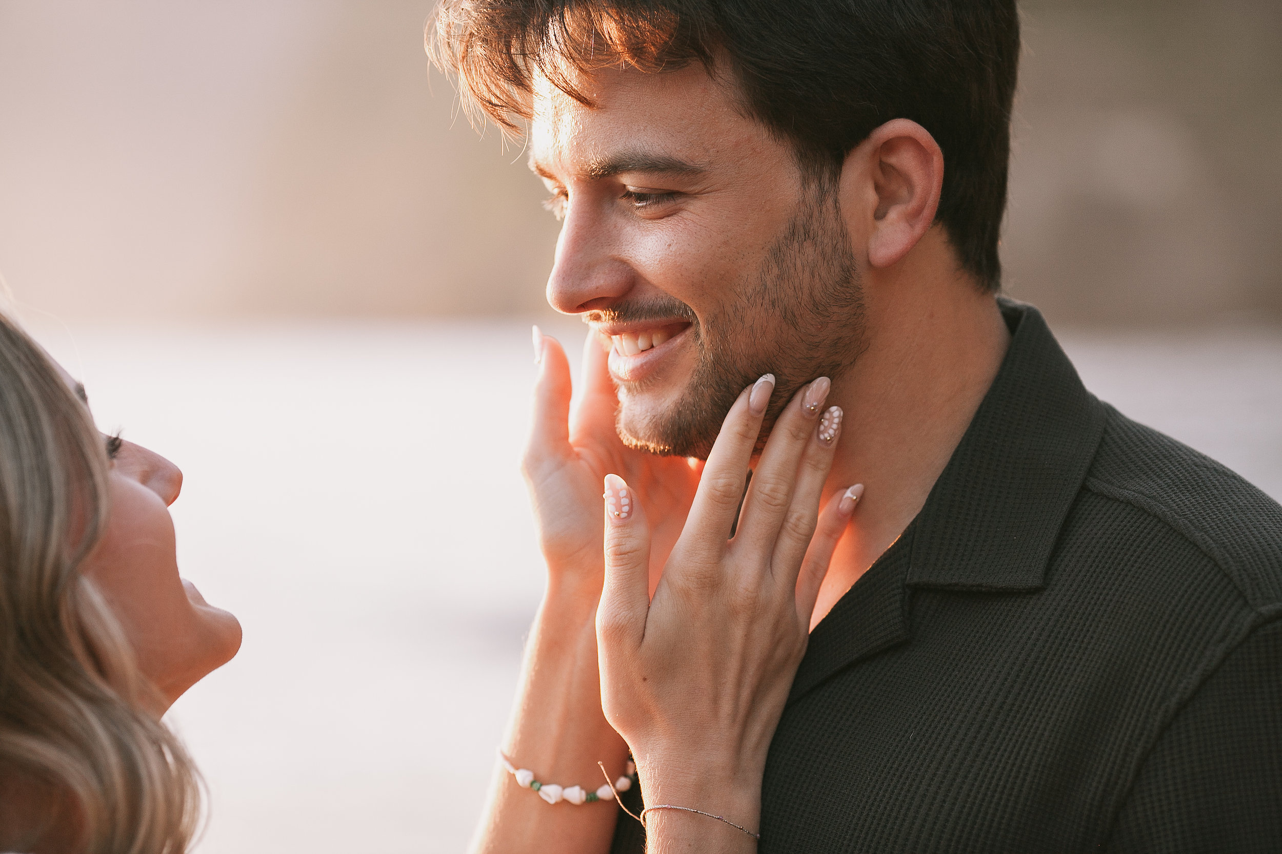 She touches his cheek as he smiles in the sunset light, Seixal, Madeira