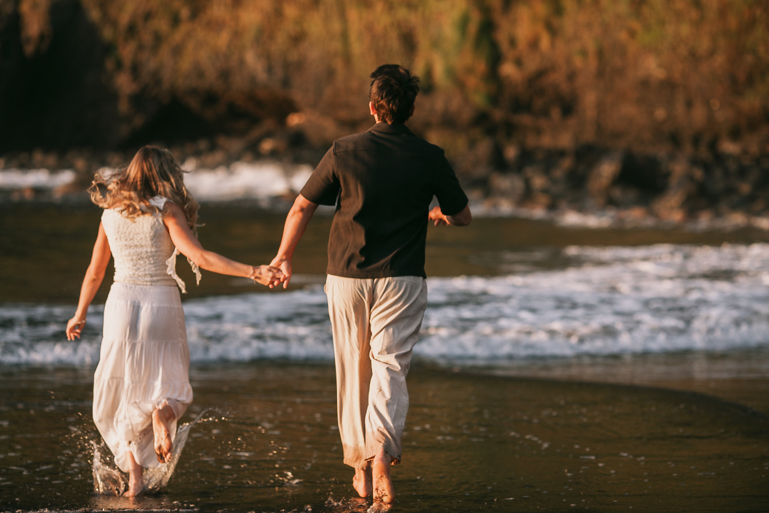 Running hand in hand through the shallows at sunset, Seixal, Madeira