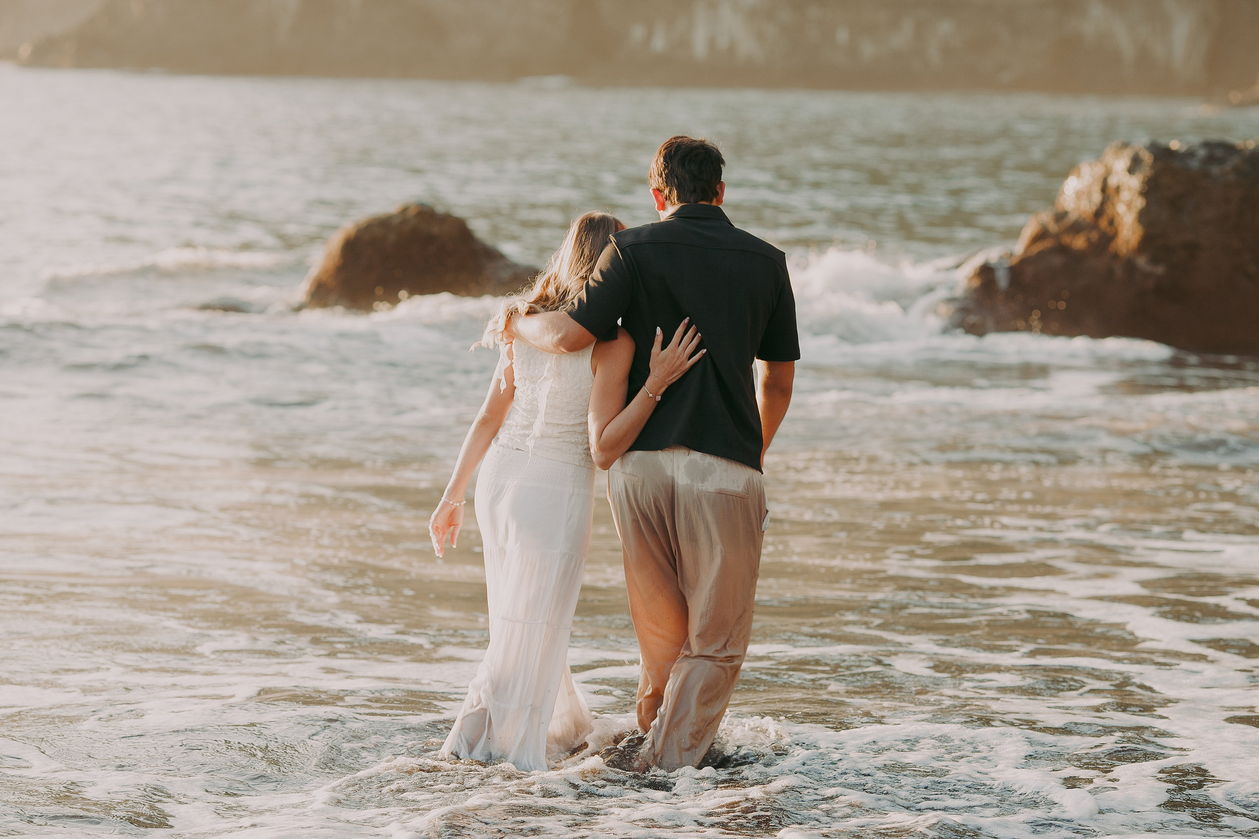 She leans back against him in the waves, Seixal Beach, Madeira