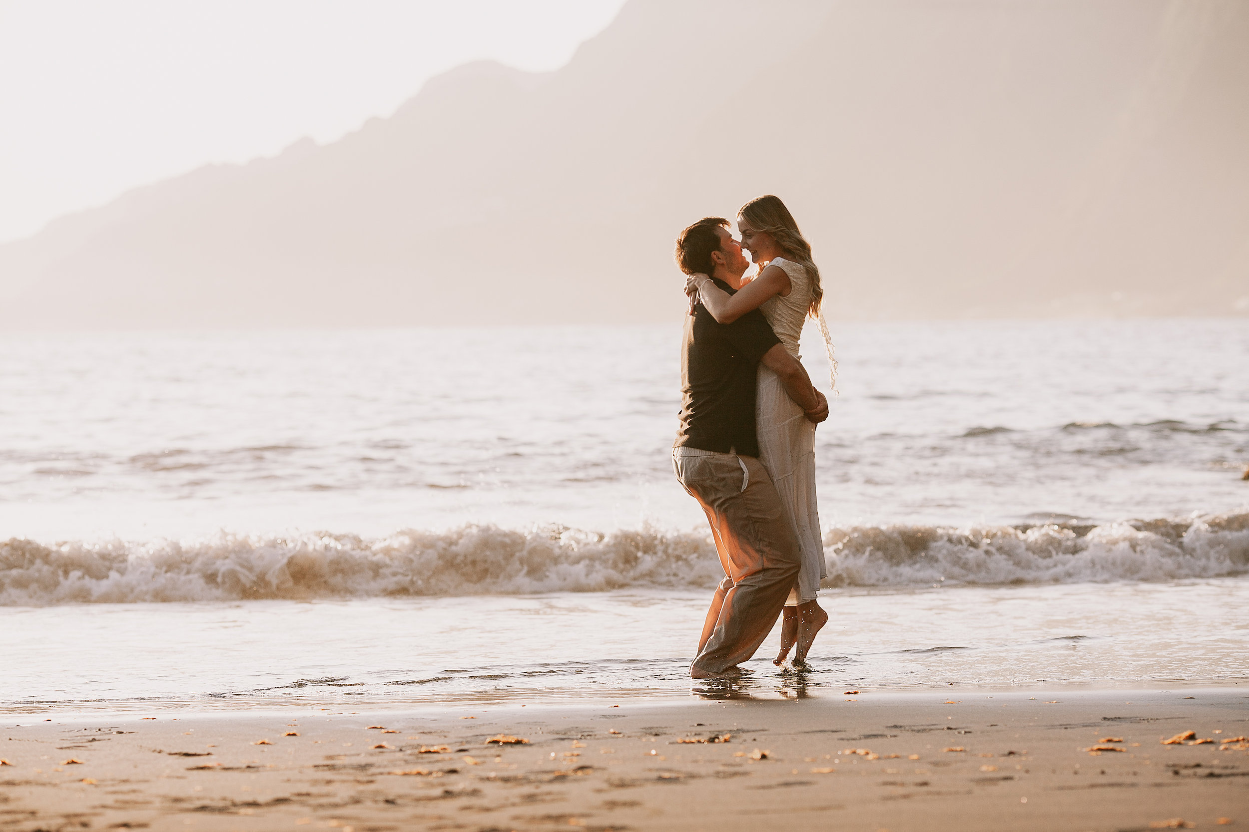He kisses her as she rests against him in the sea, Seixal Beach, Madeira