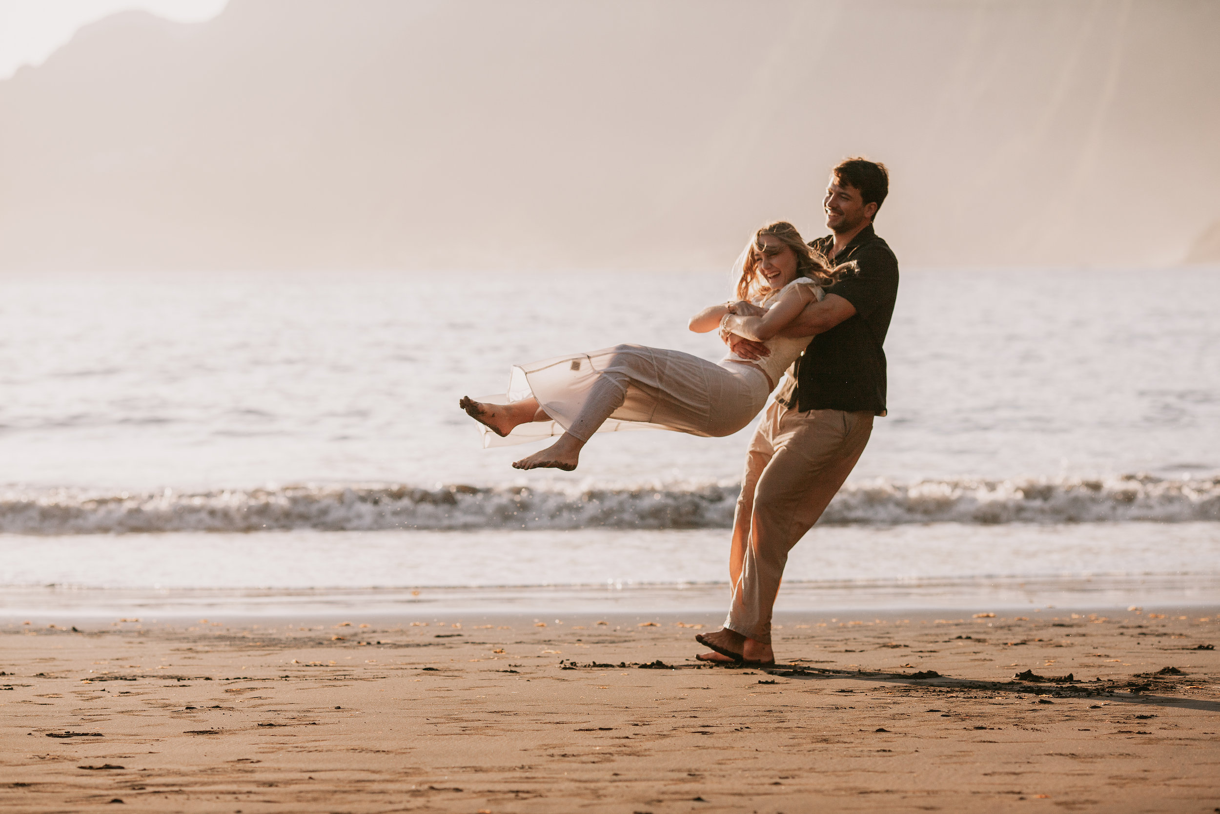 He carries her in his arms across the sand, Seixal Beach, Madeira