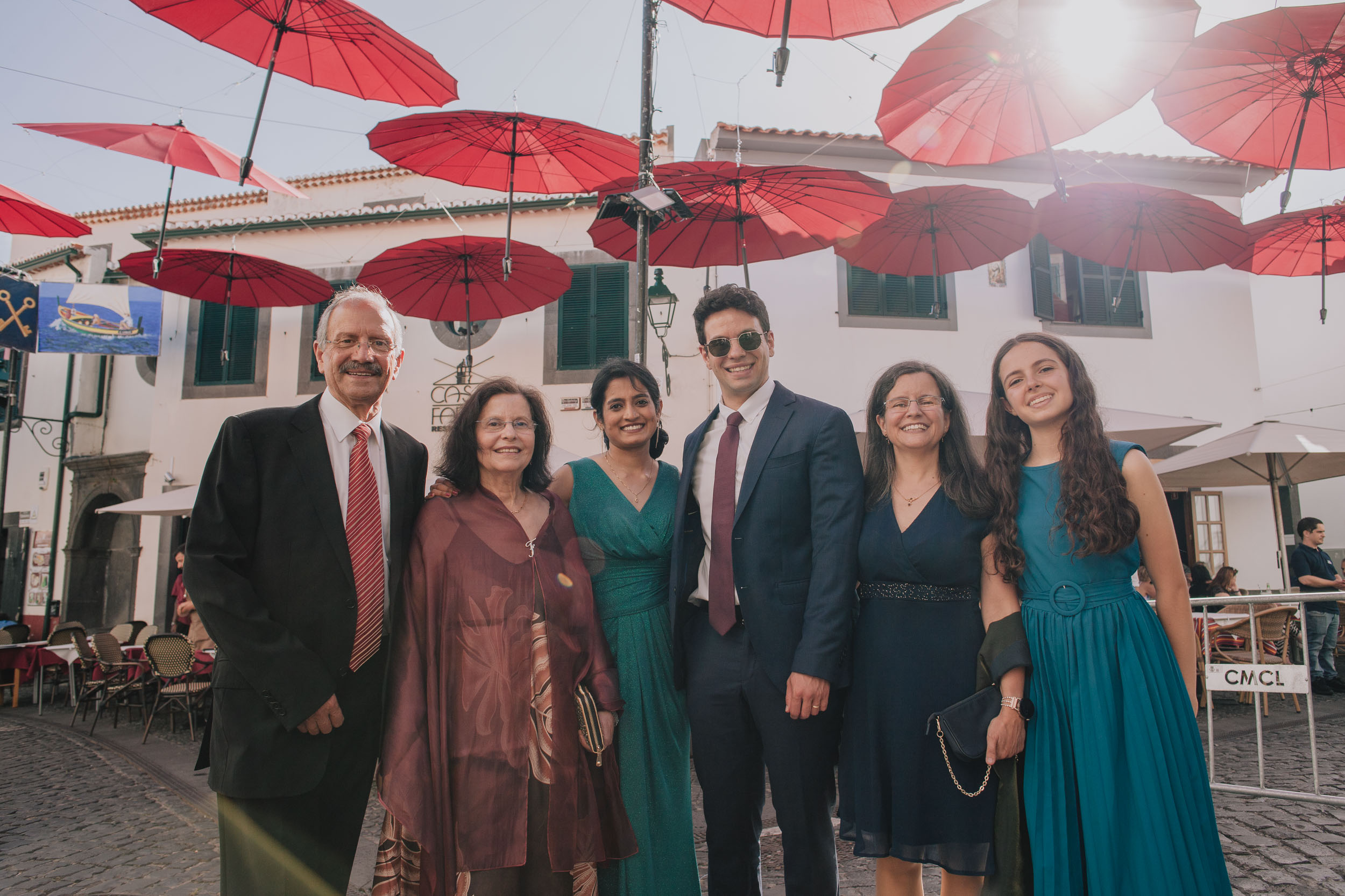 Wedding family group of six under the red umbrellas in the square at Câmara de Lobos, Madeira