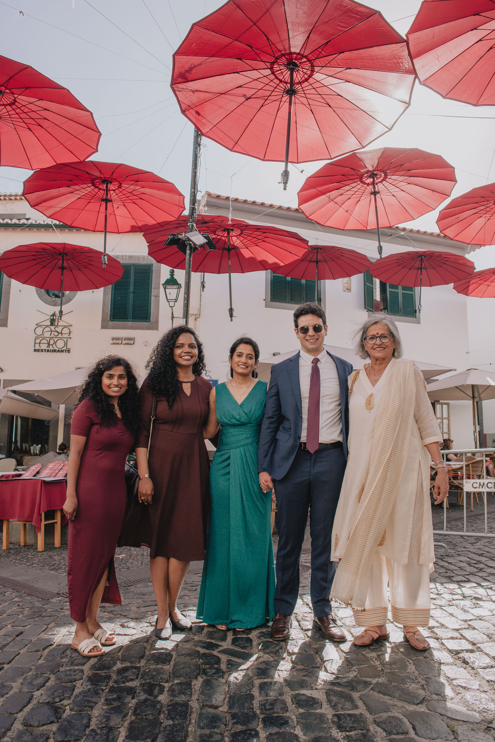 Groom with the bride and three guests under the red umbrellas of Câmara de Lobos, Madeira