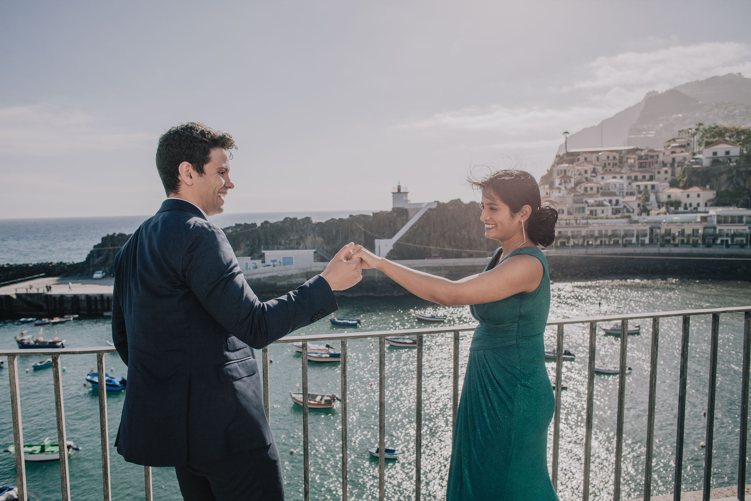 Groom turning the bride by the hand like a dance, the harbour and lighthouse pier behind, Câmara de Lobos, Madeira