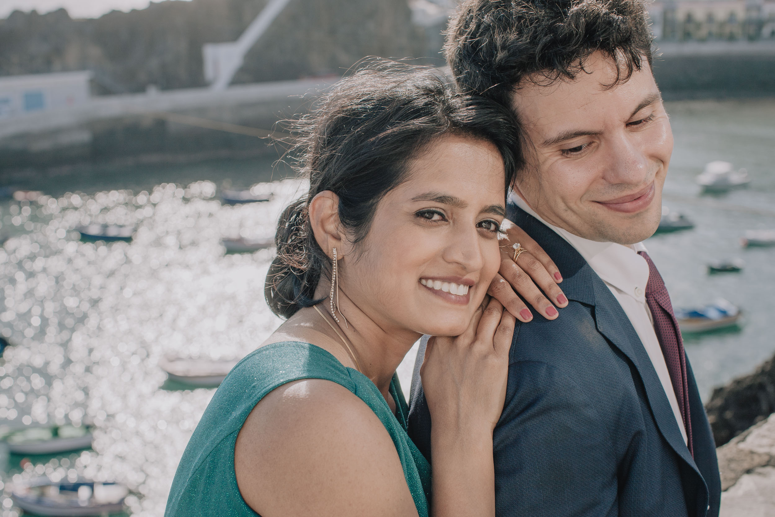 Bride leaning into the groom, both smiling, the harbour and its boats behind, Câmara de Lobos, Madeira
