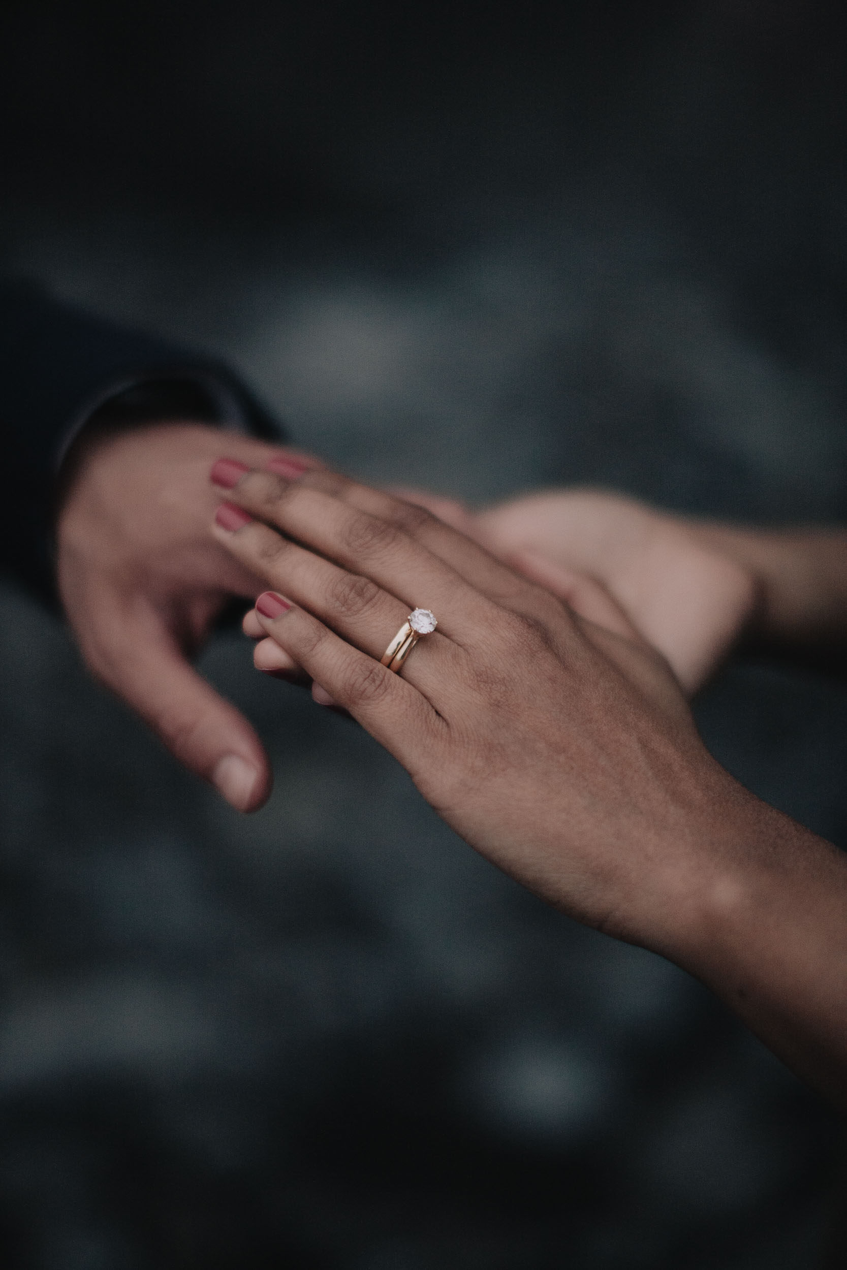 Close detail of the bride's hand with diamond and wedding rings resting over the groom's hand, Câmara de Lobos, Madeira