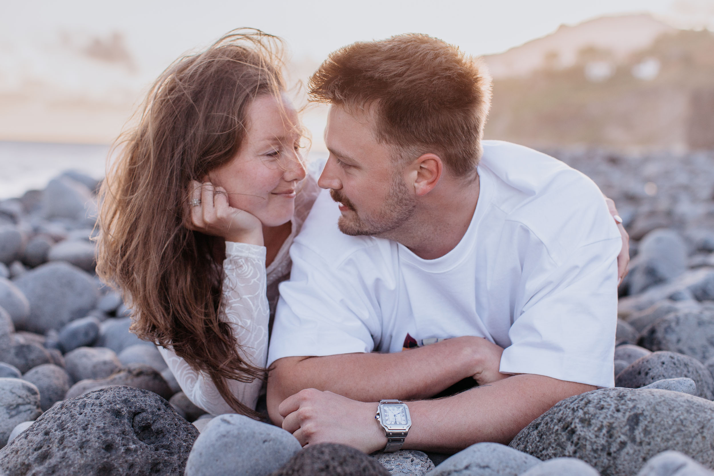 Lying together on the round grey pebbles, face to face, her hand under her cheek, Praia Formosa, Madeira