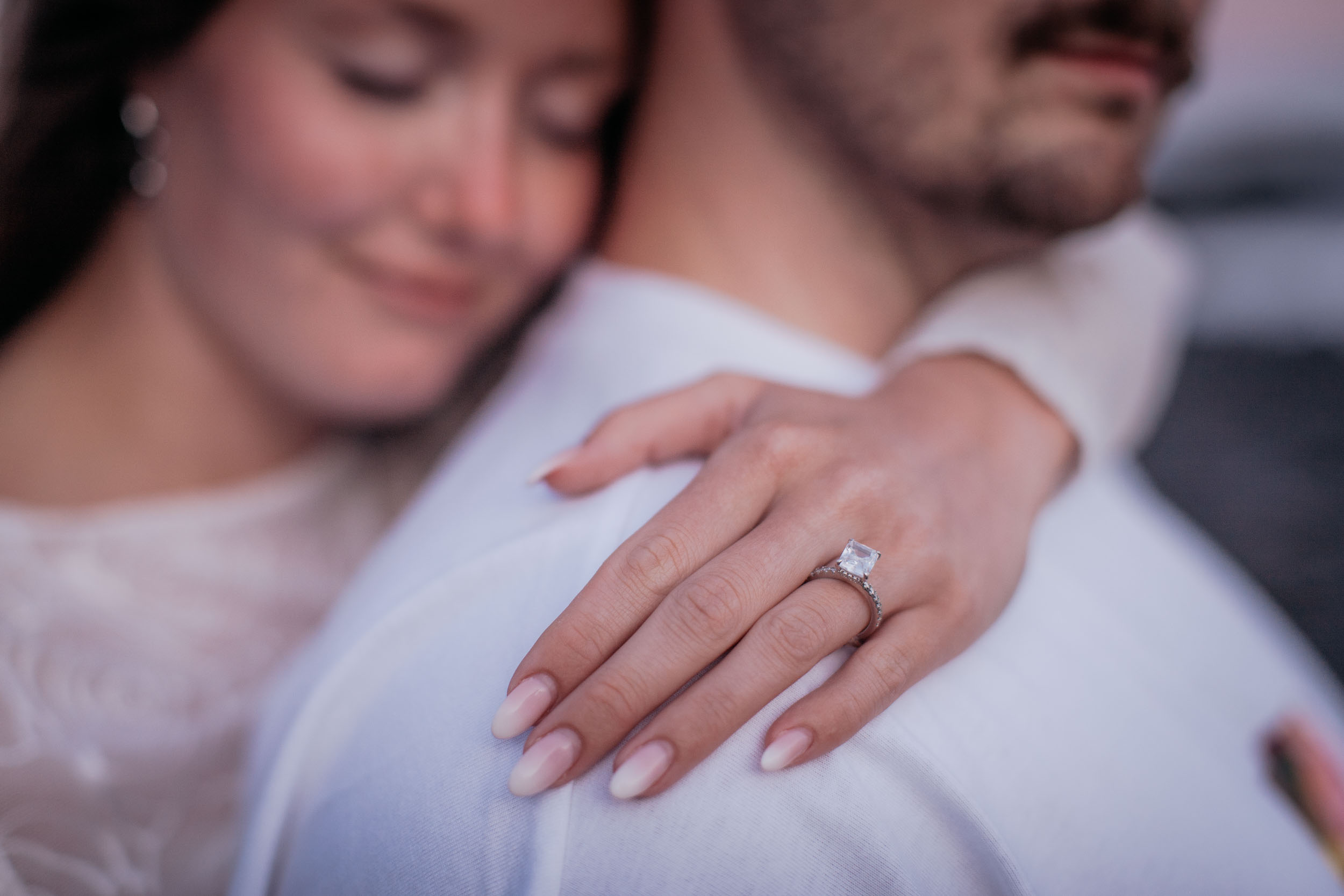 Close detail of Abby's engagement ring on her hand resting on Rylie's shoulder, her face soft in the background, Praia Formosa, Madeira
