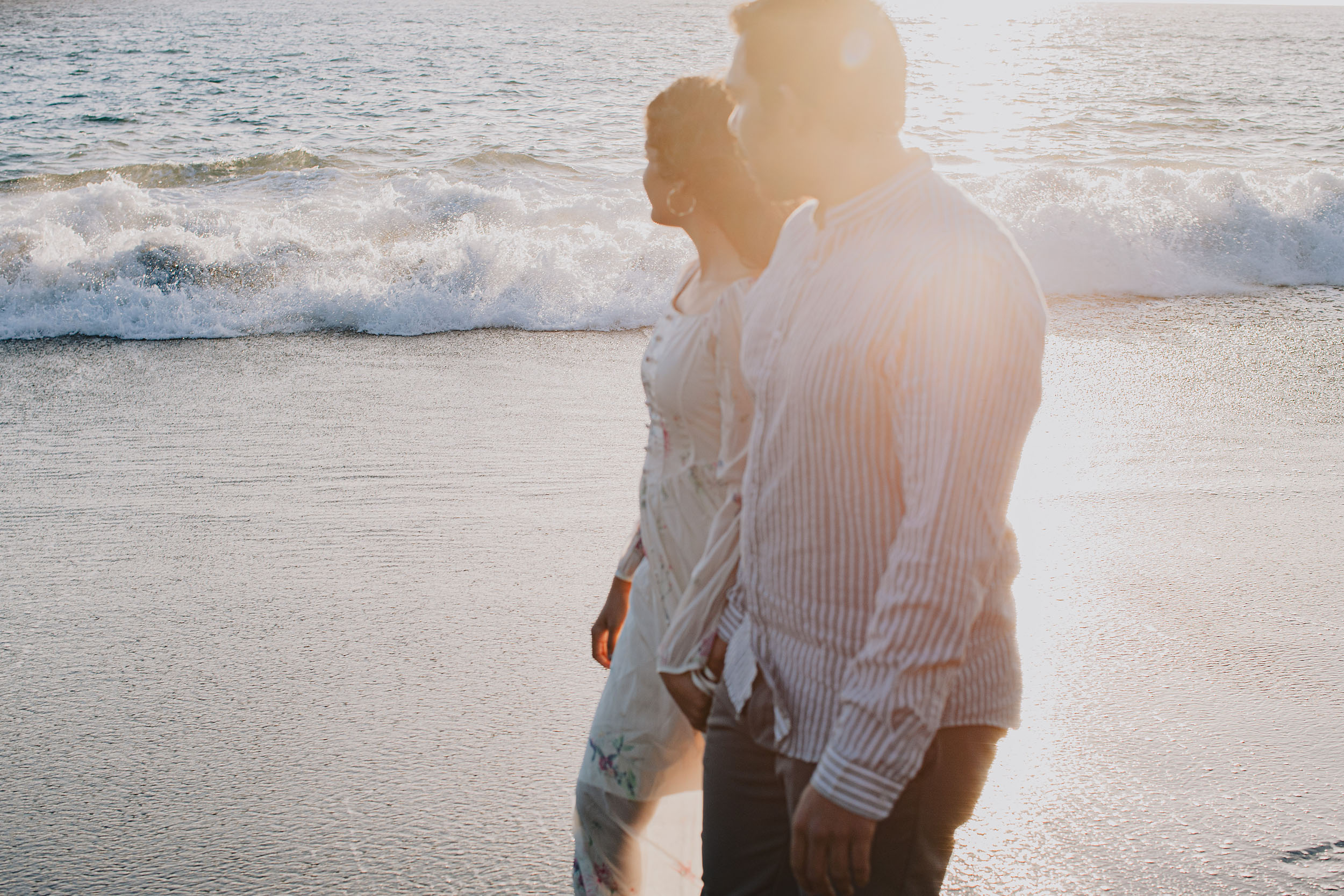 Couple at Praia Formosa shoreline, strong backlit golden sunset light silhouetting them against the Atlantic, Funchal, Madeira