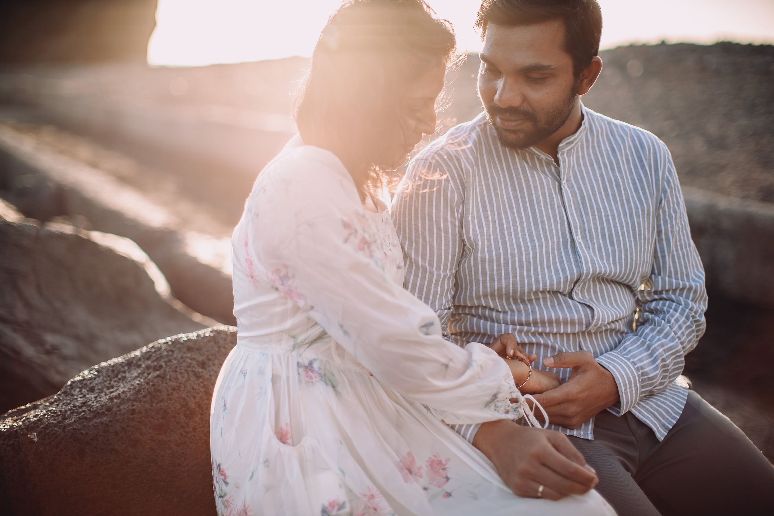 Couple on volcanic rocks at Praia Formosa, strong golden lens flare, Saket gazing tenderly at Sneha, Funchal, Madeira