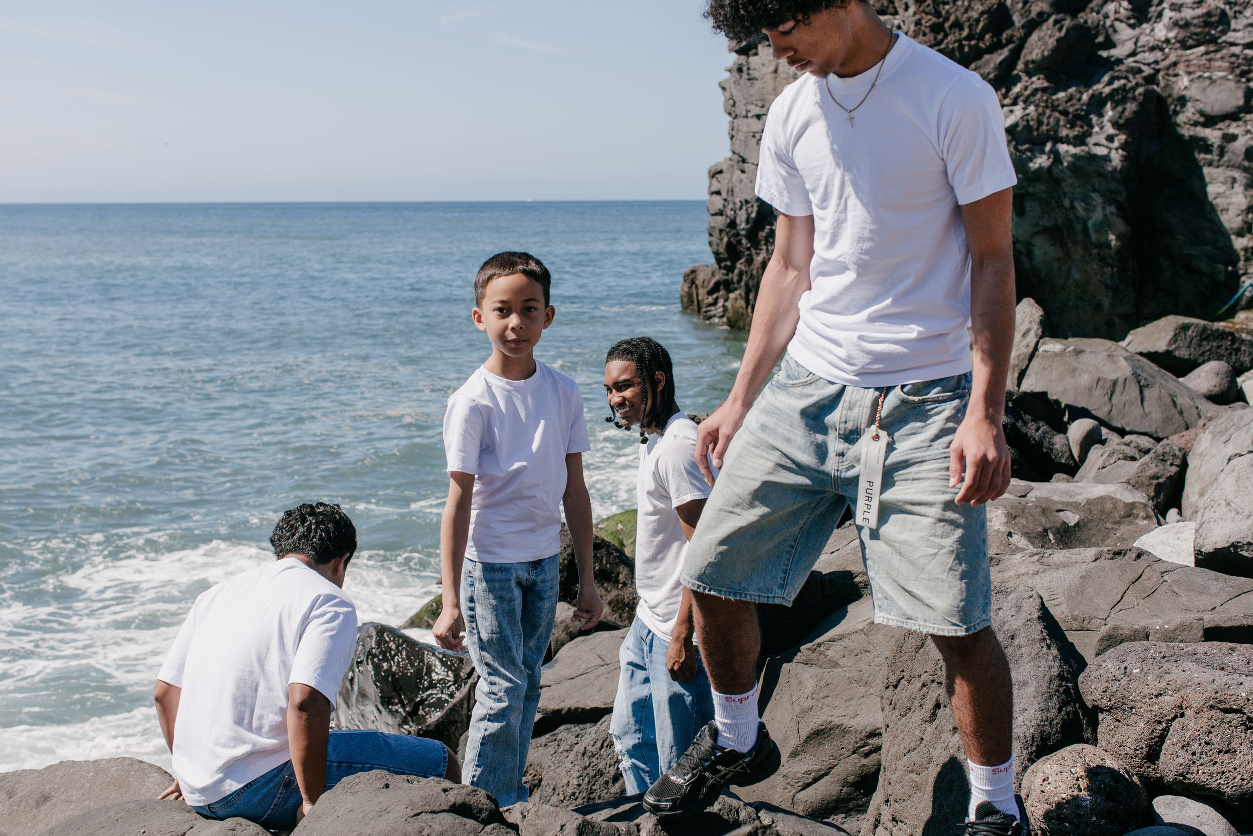 Sons climbing the volcanic boulders at the shoreline, the young boy smiling to camera, Praia Formosa, Madeira