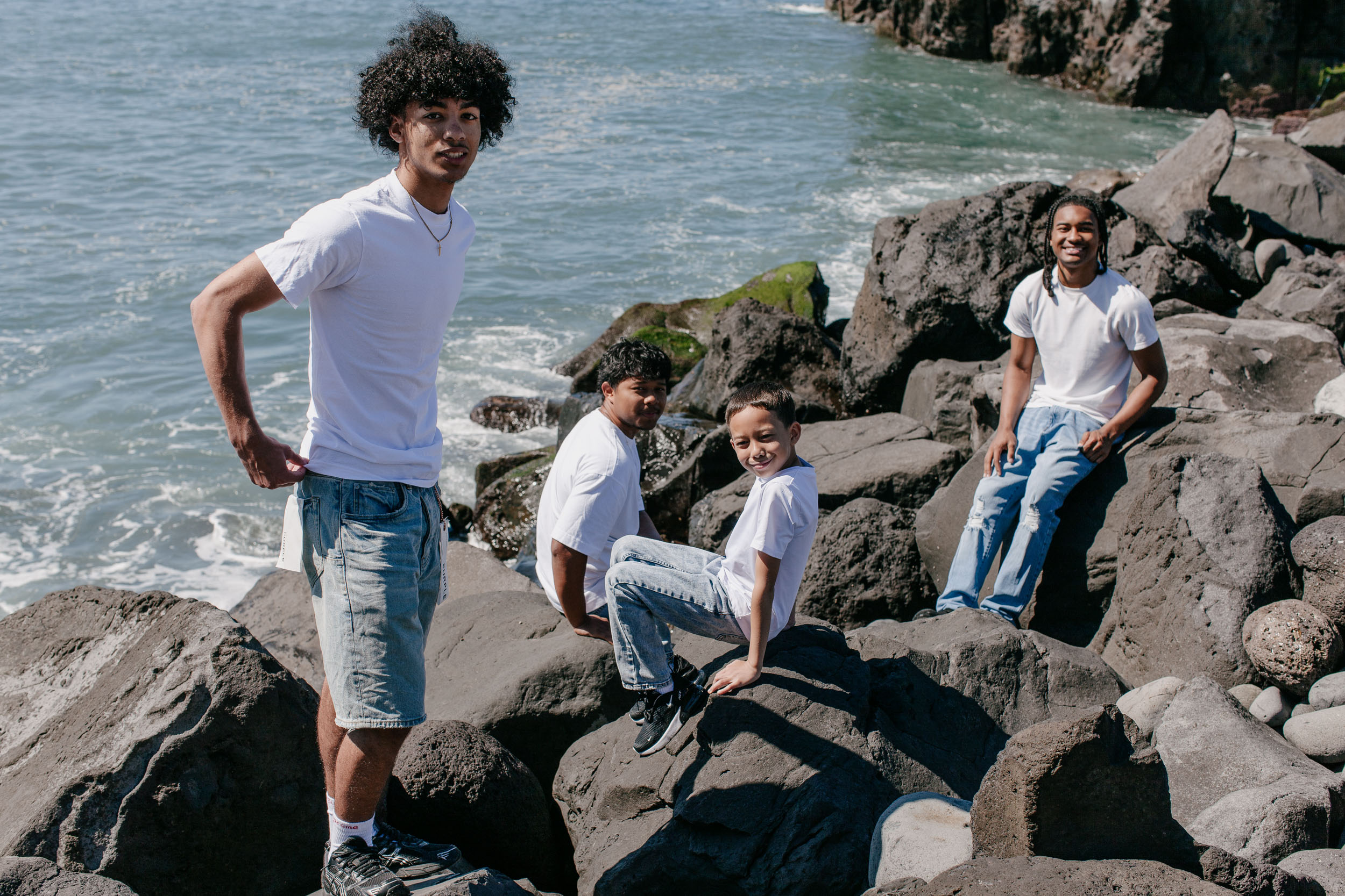 Four brothers resting on the volcanic rocks above the surf, Praia Formosa, Funchal, Madeira