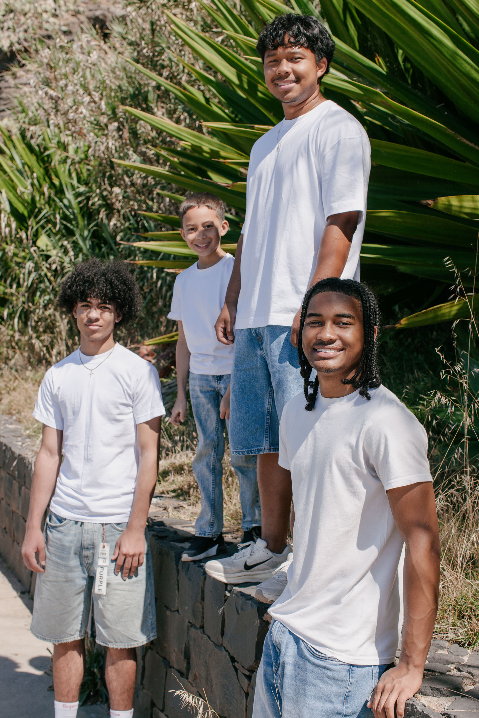 Four brothers by a stone wall with agave behind, relaxed and smiling to camera, Praia Formosa, Funchal, Madeira