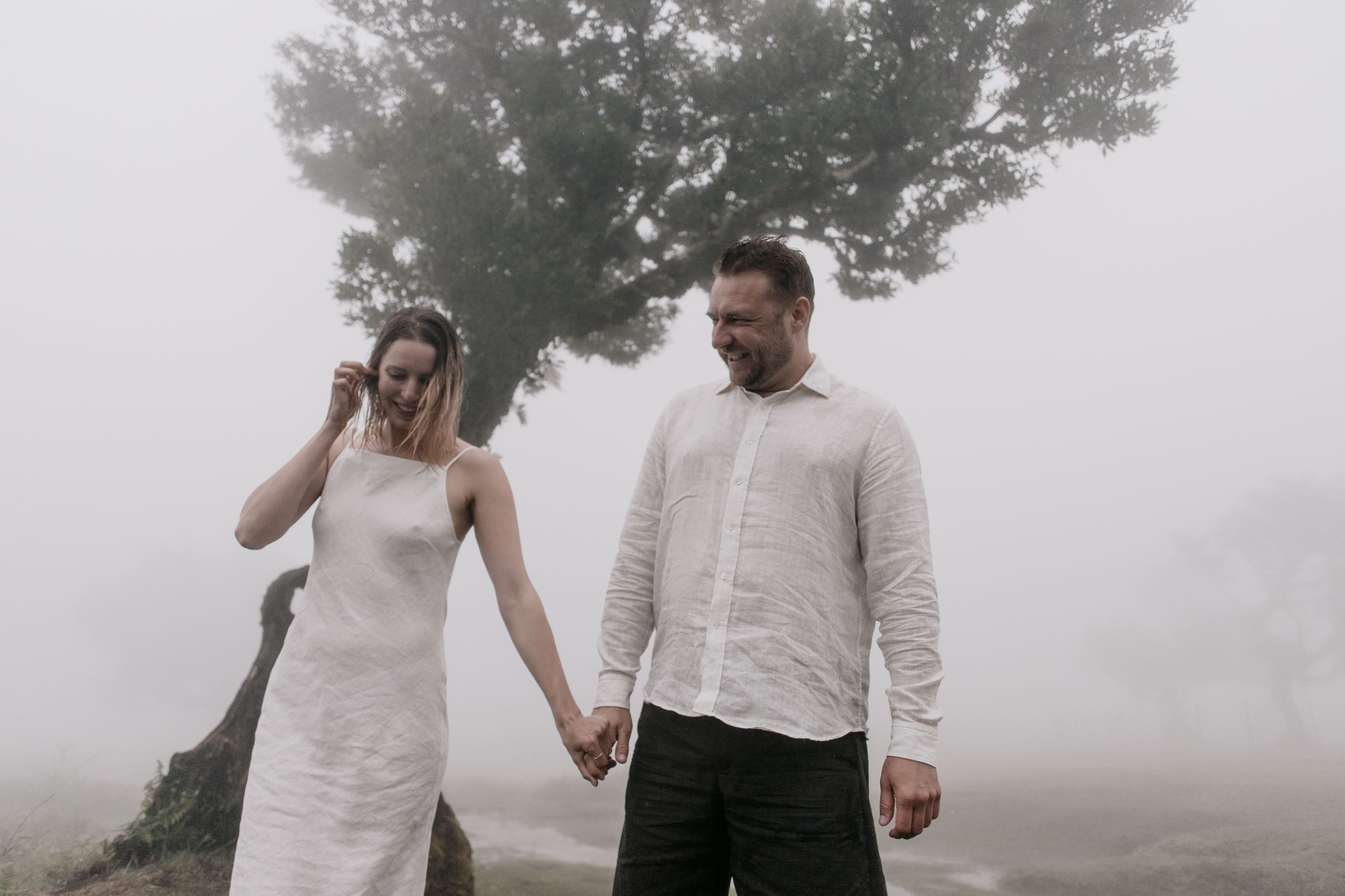 Couples portrait in the mist of Fanal Forest, gnarled laurel trunks framing the figures, Madeira