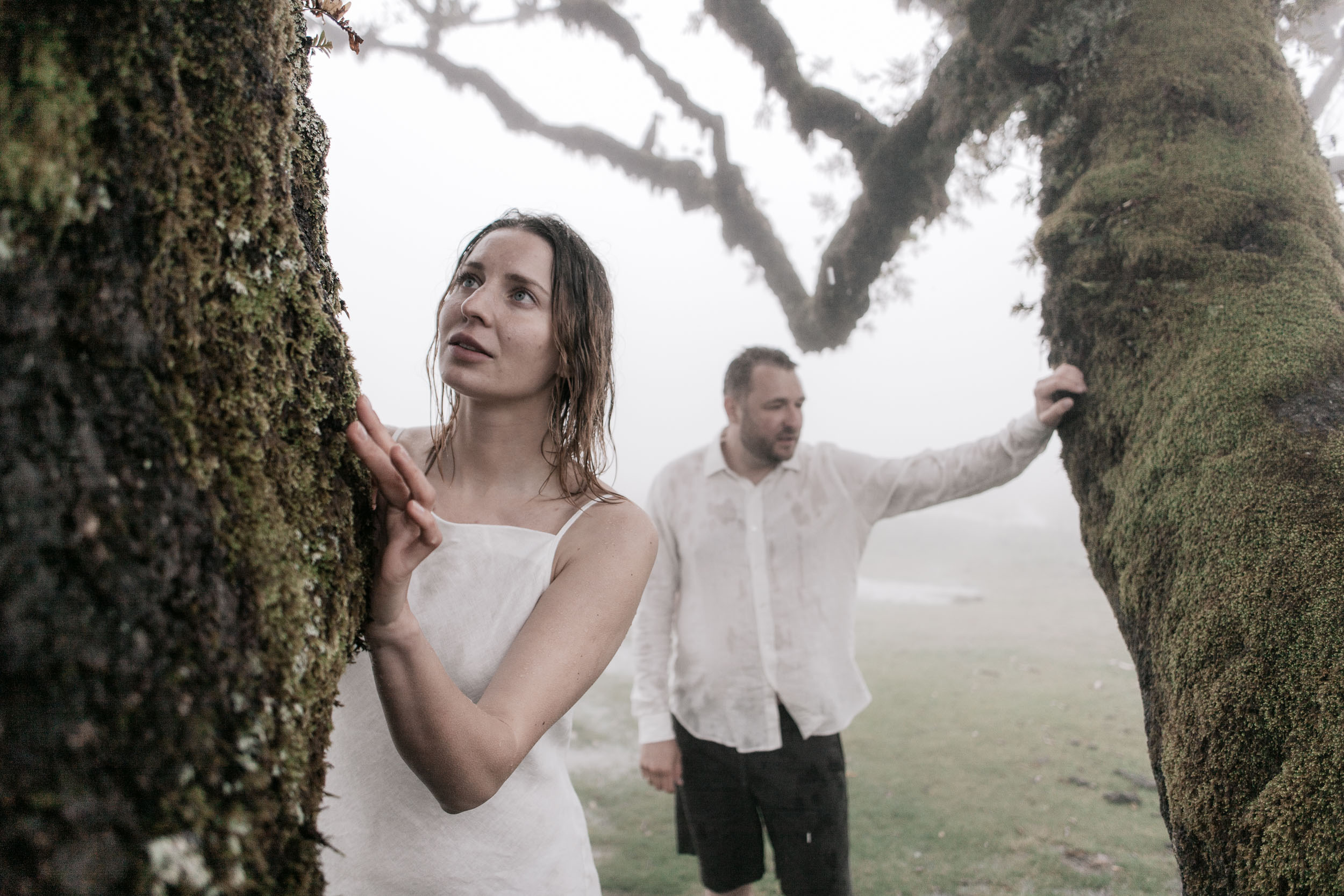 Solo portrait of a woman in white under ancient laurel branches, heavy fog, Fanal Forest, Madeira