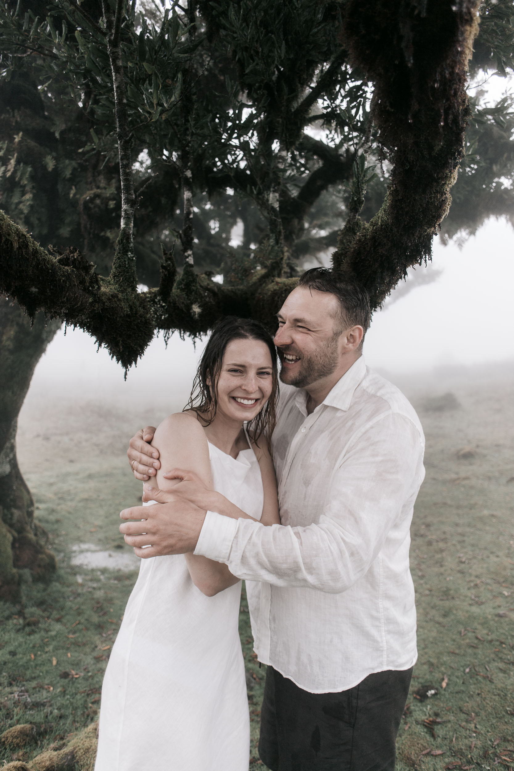 Couple holding hands under the laurels at Fanal, dense fog behind, Madeira