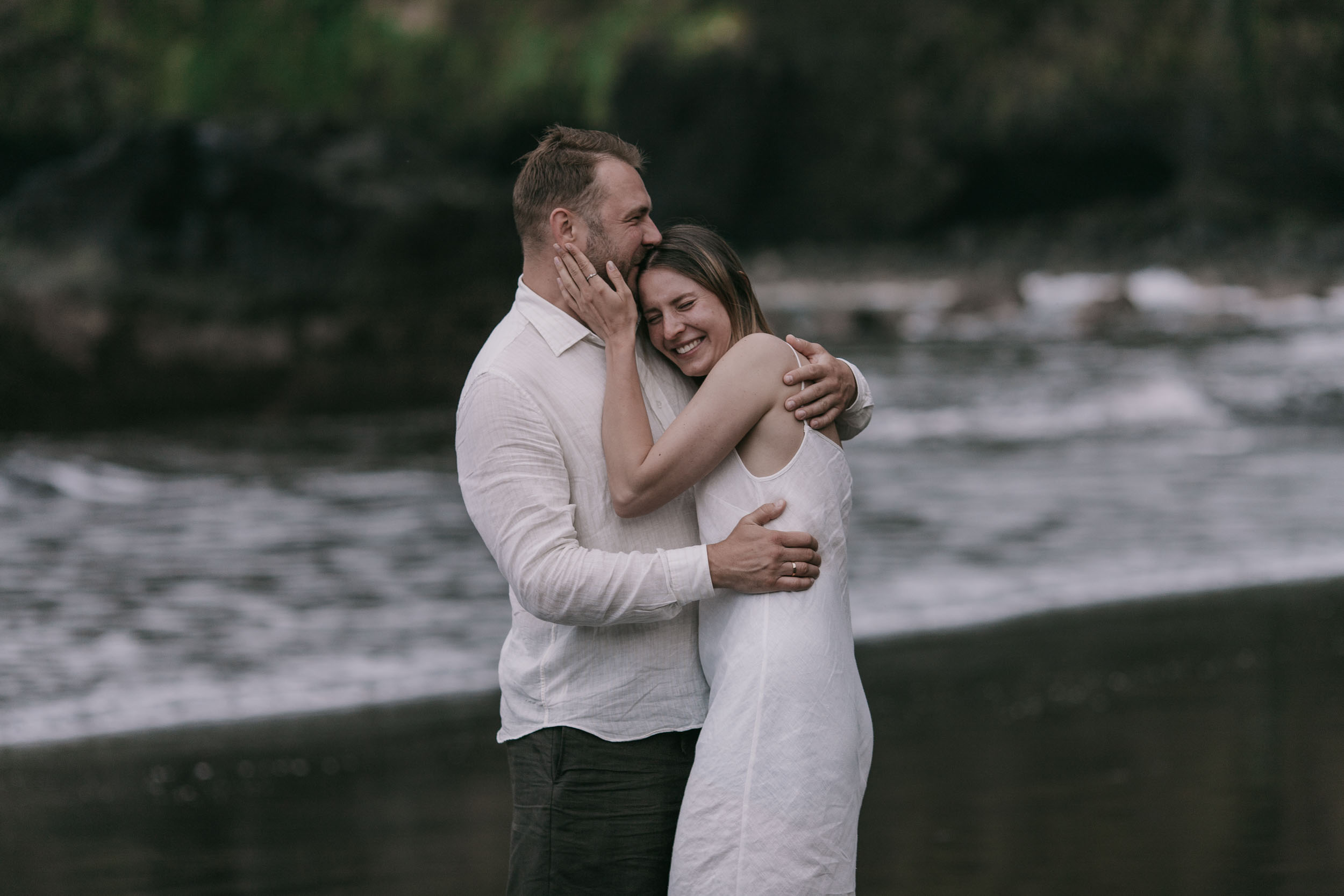Quiet hug on a black sand beach, dramatic green cliffs behind, Madeira