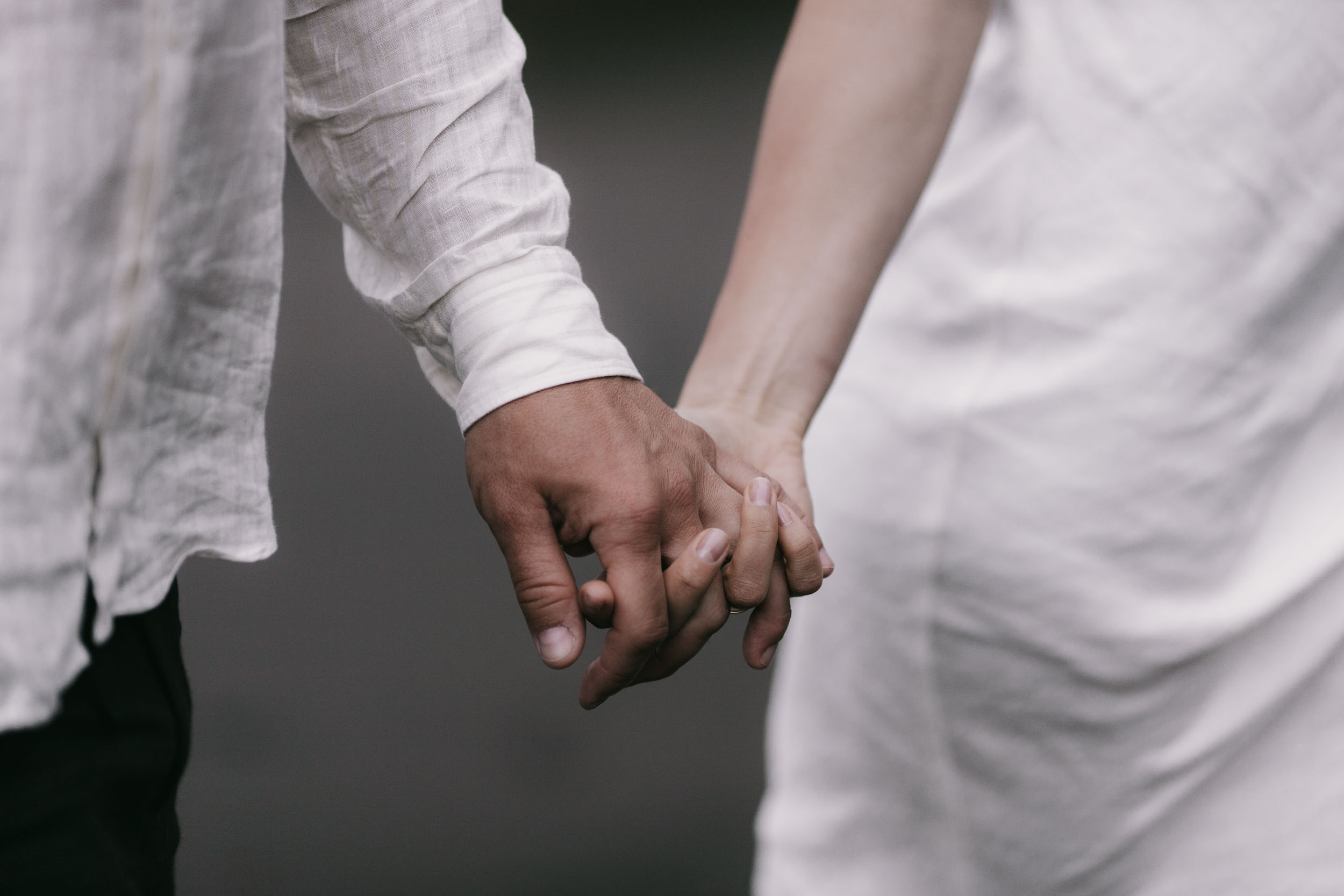 She rests her cheek on his shoulder, both in white, dark beach, north Madeira