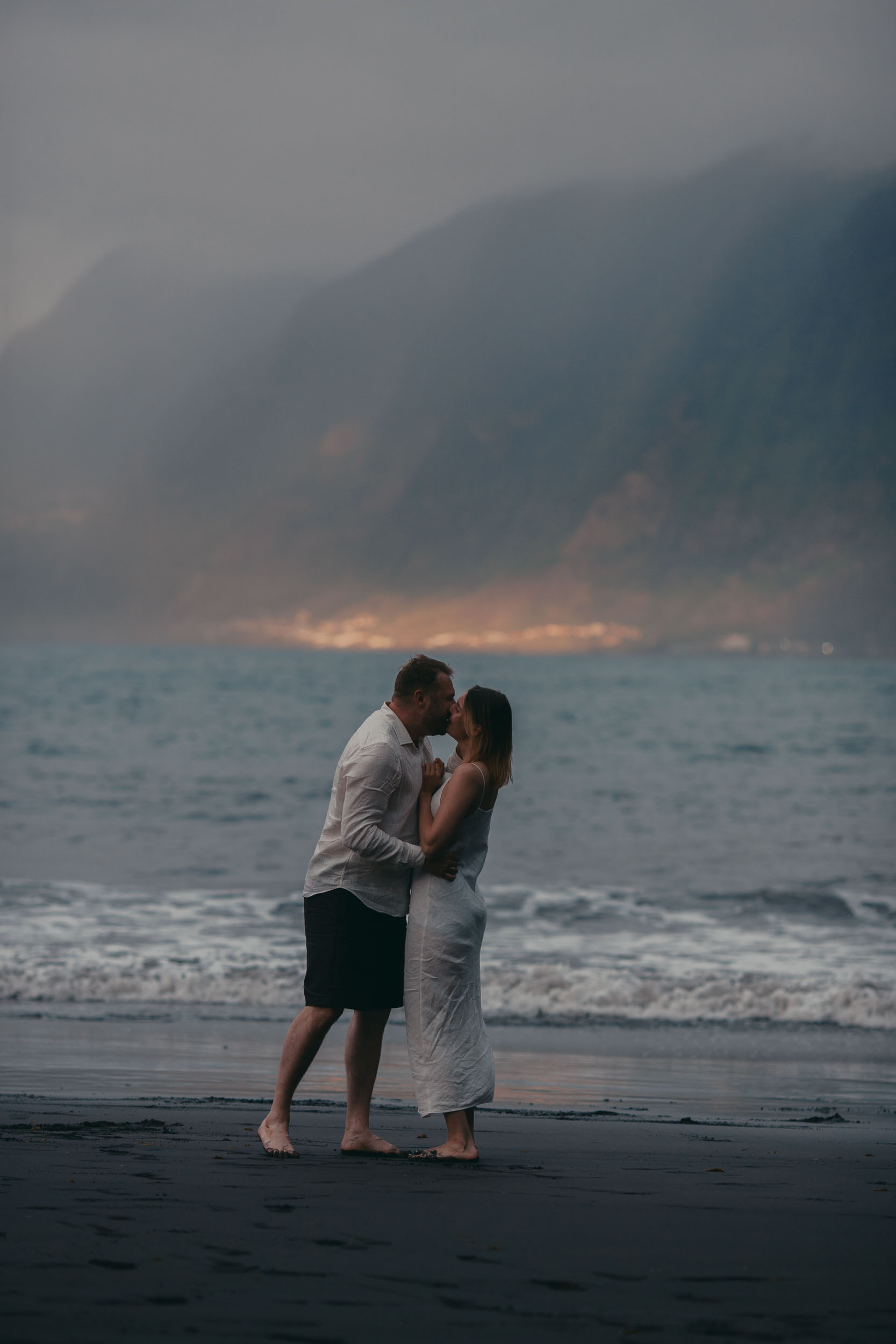 Close intimate moment at golden hour, the couple in soft warm light, Atlantic behind, Madeira