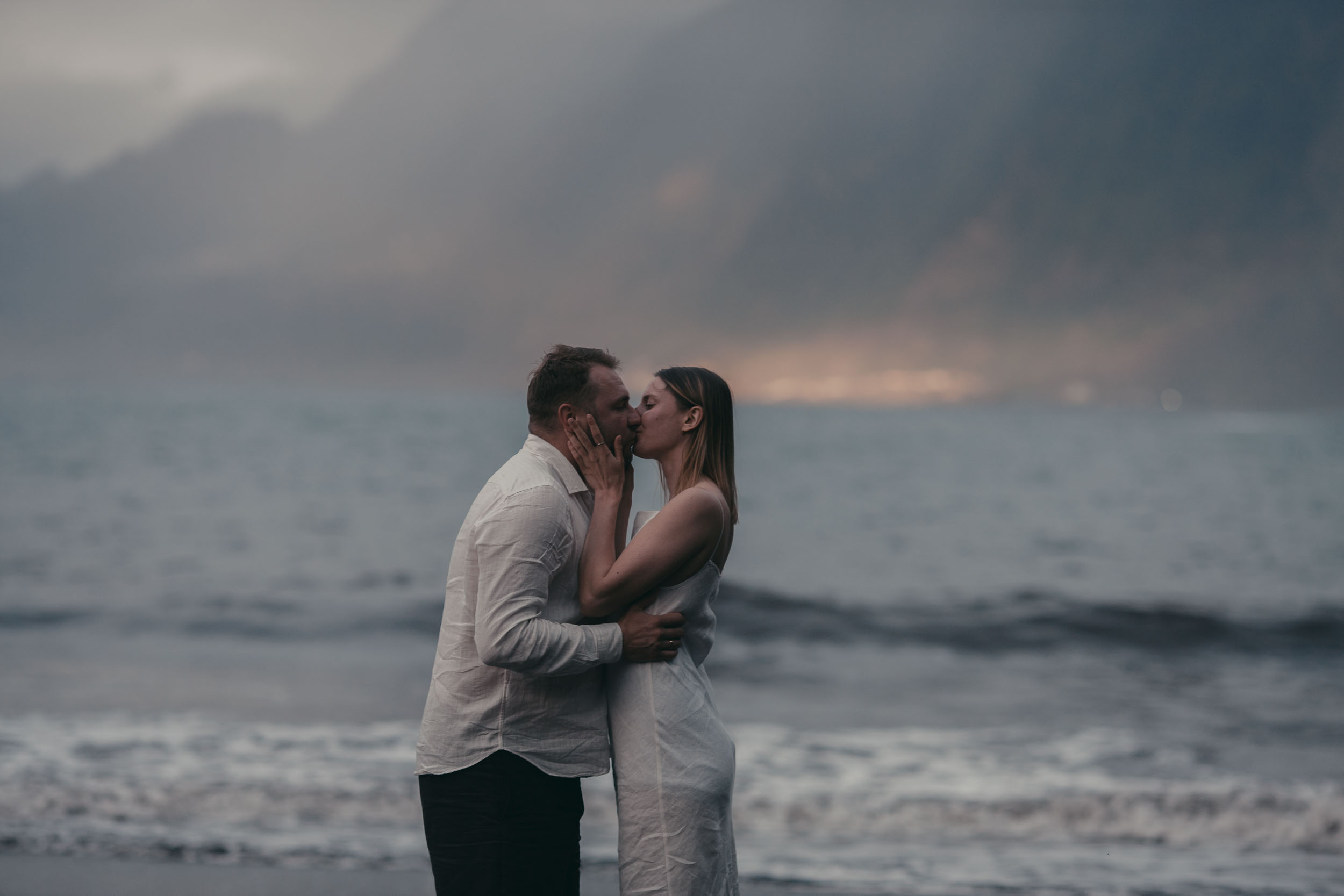 Quiet embrace at last light on a black sand beach, fading sun on the water, north Madeira