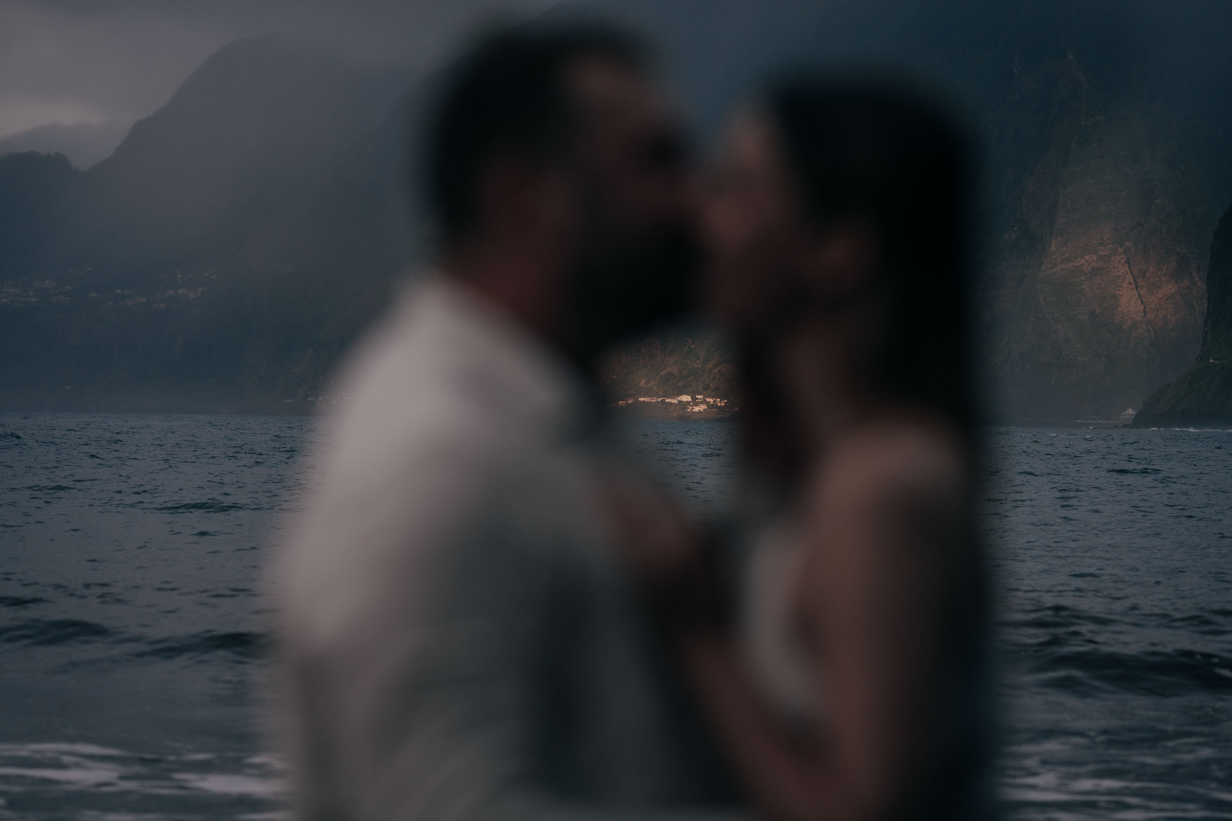 Couple in white at the edge of the surf during golden hour, soft focus and warm tones, Madeira