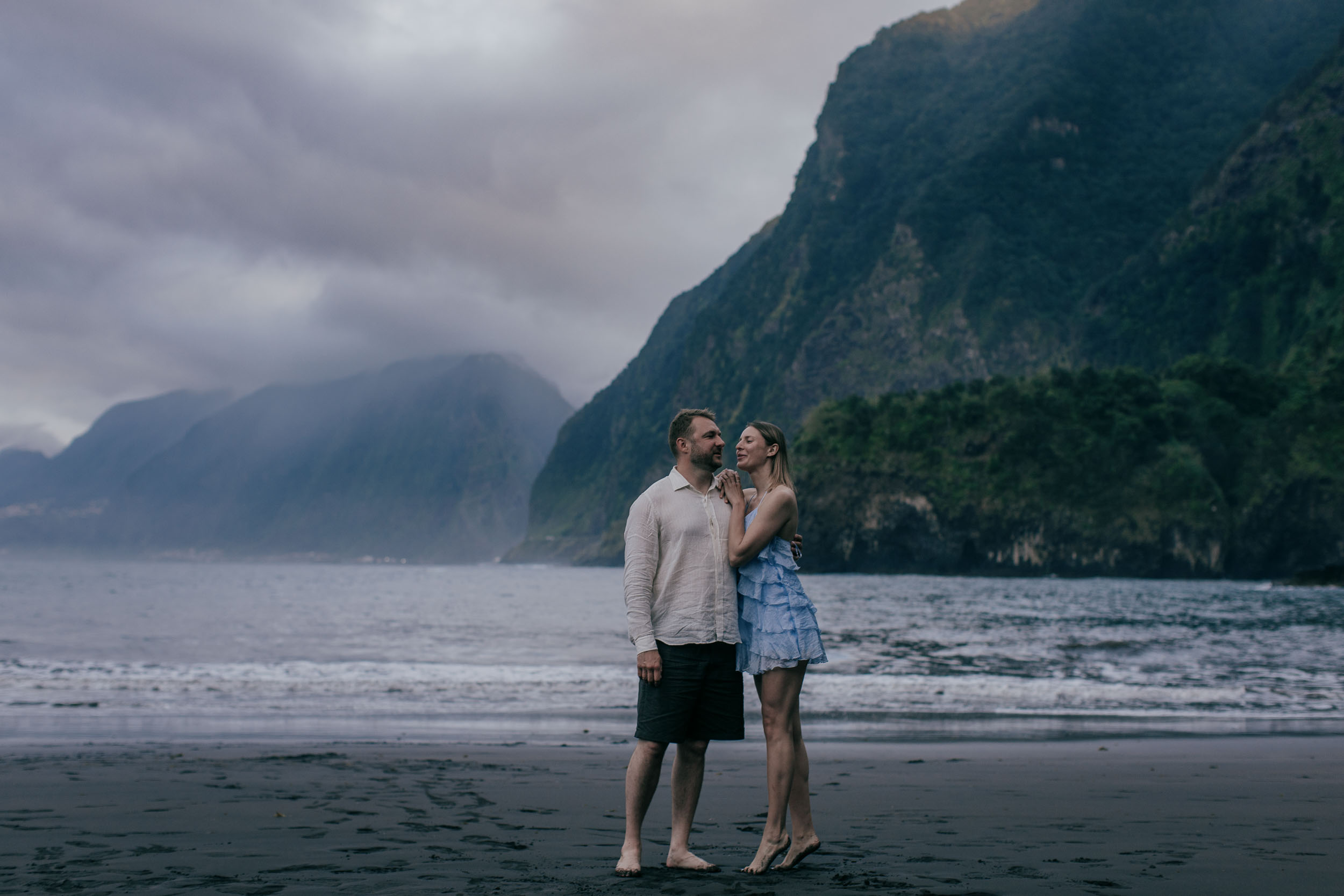 Quiet embrace at last light on a black sand beach, fading sun on the water, north Madeira