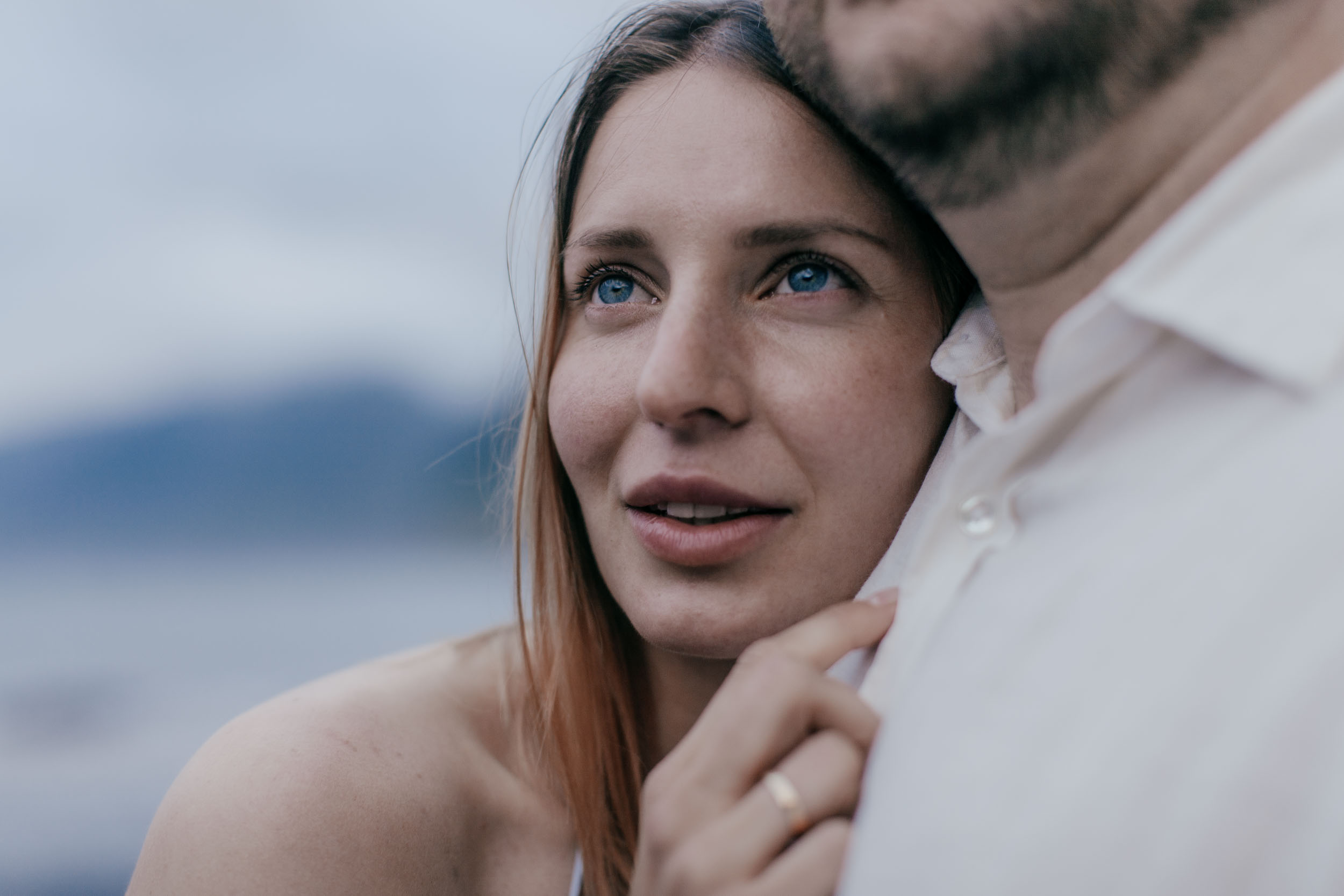 Close detail of two hands together with rings, the couple smiling in the background, Madeira