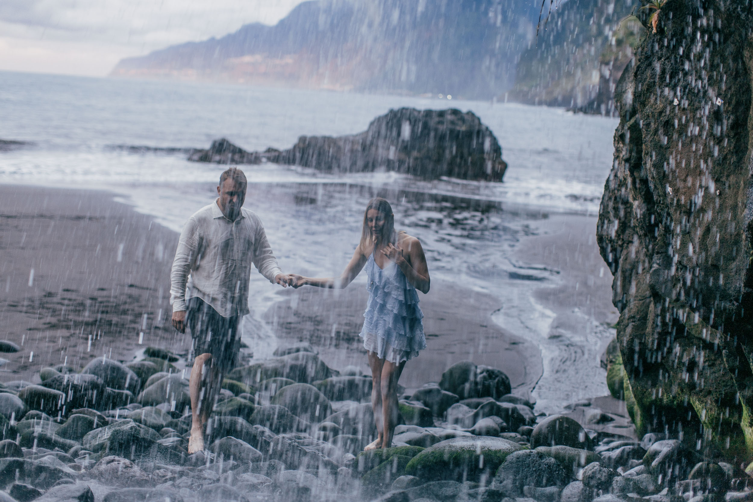 Couple at the base of jagged sea stacks, soft sunset light, north Madeira