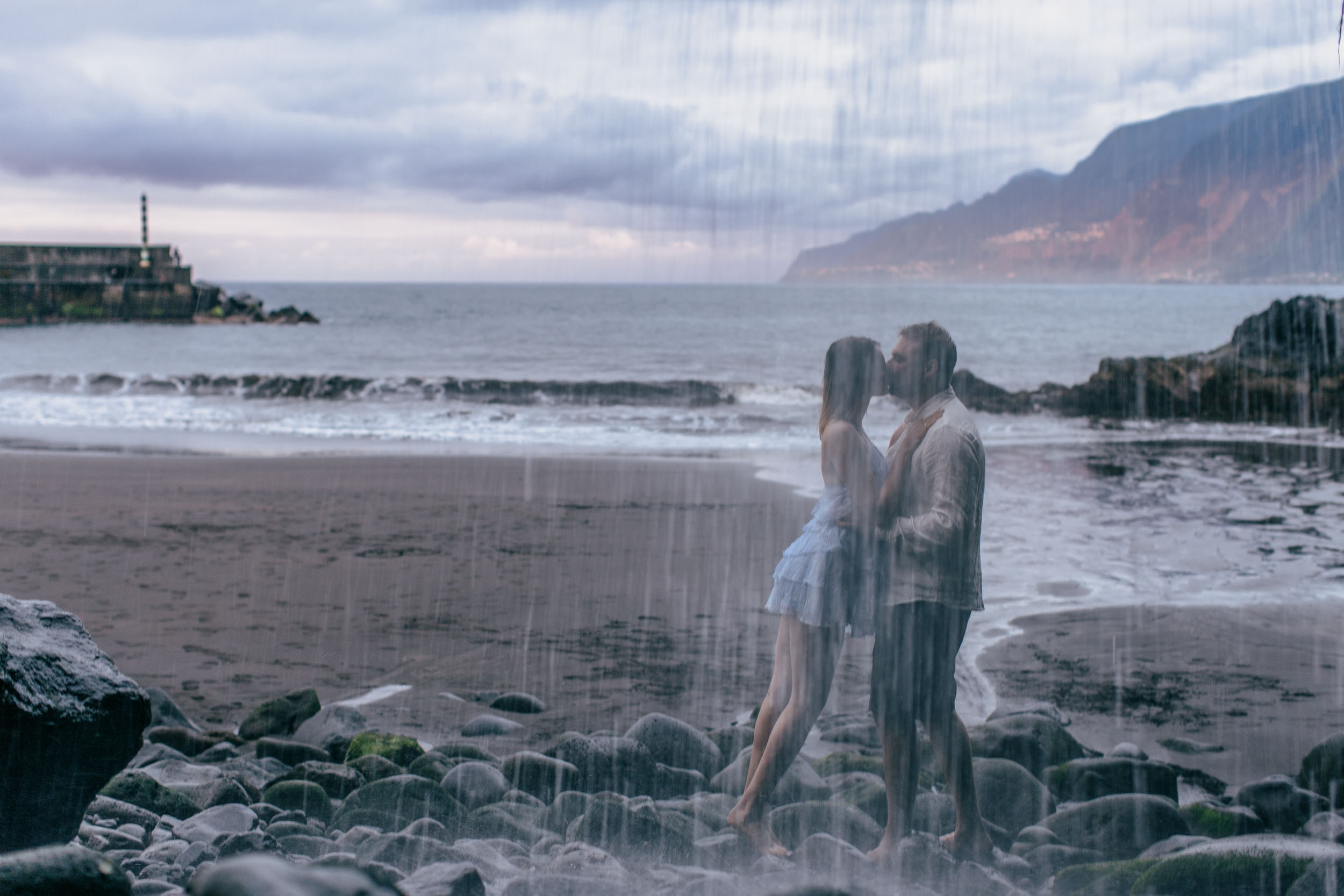 Couple by dramatic volcanic rock outcrops on the north Madeira coast, fading light