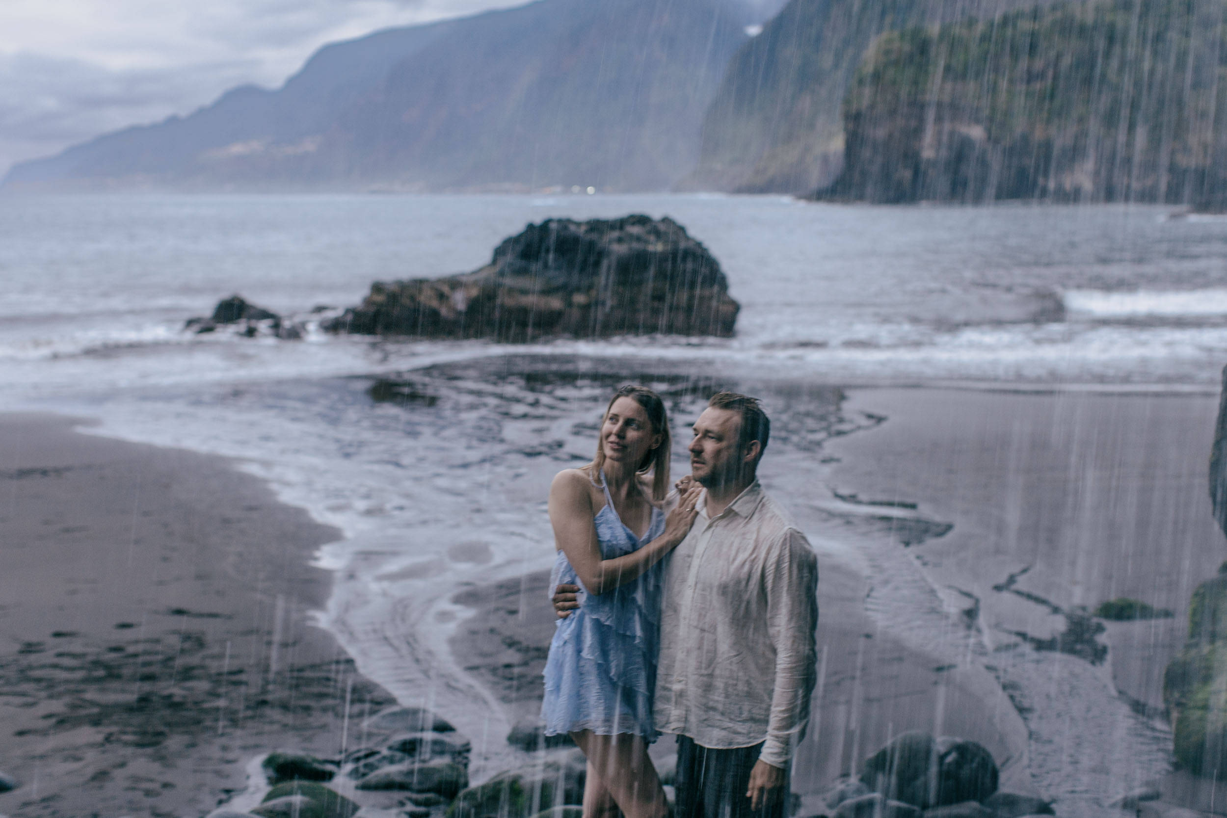 Couple at the base of jagged sea stacks, soft sunset light, north Madeira